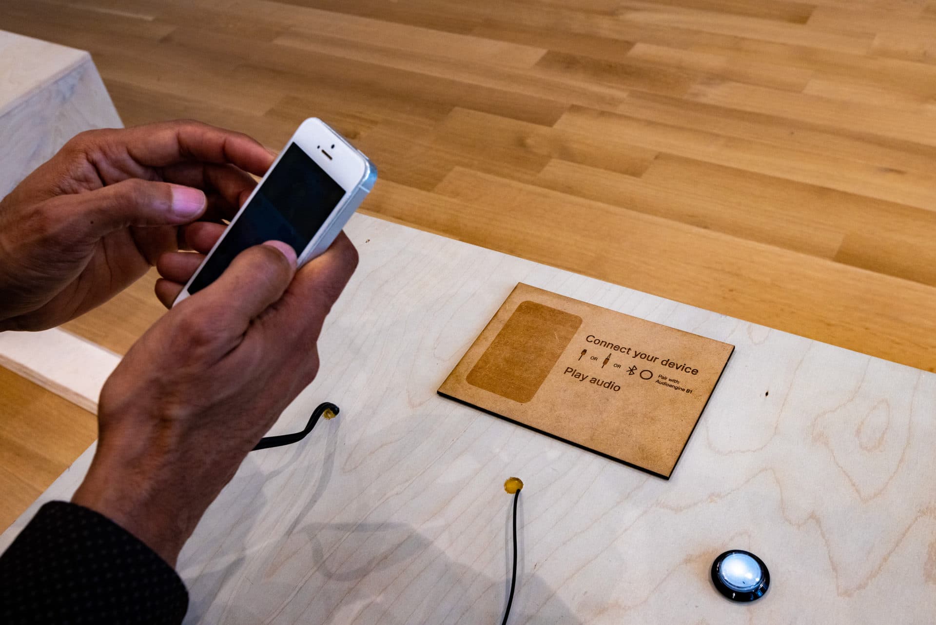 Artist Jace Clayton demonstrates connecting his smartphone in the center of “40 Part Part,” an interactive installation, one of three installations by the artist in the show “They Are Part” at the MAAM. (Jesse Costa/WBUR)