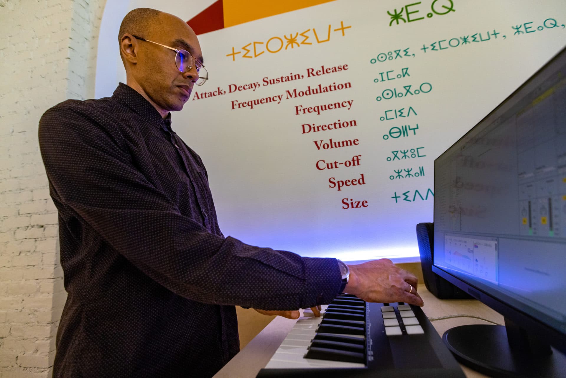 Artist Jace Clayton demonstrates a synthesizer tuned to the Arabic music scale in the installation “Sufi Plug Ins,” one of three installations by the artist in the show “They Are Part” at the MAAM. (Jesse Costa/WBUR)