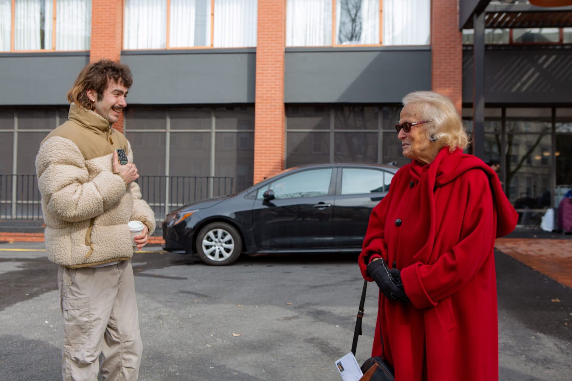 Alden McWayne compliments Nancy Korman on her red coat. (Jacob Garcia/WBUR)