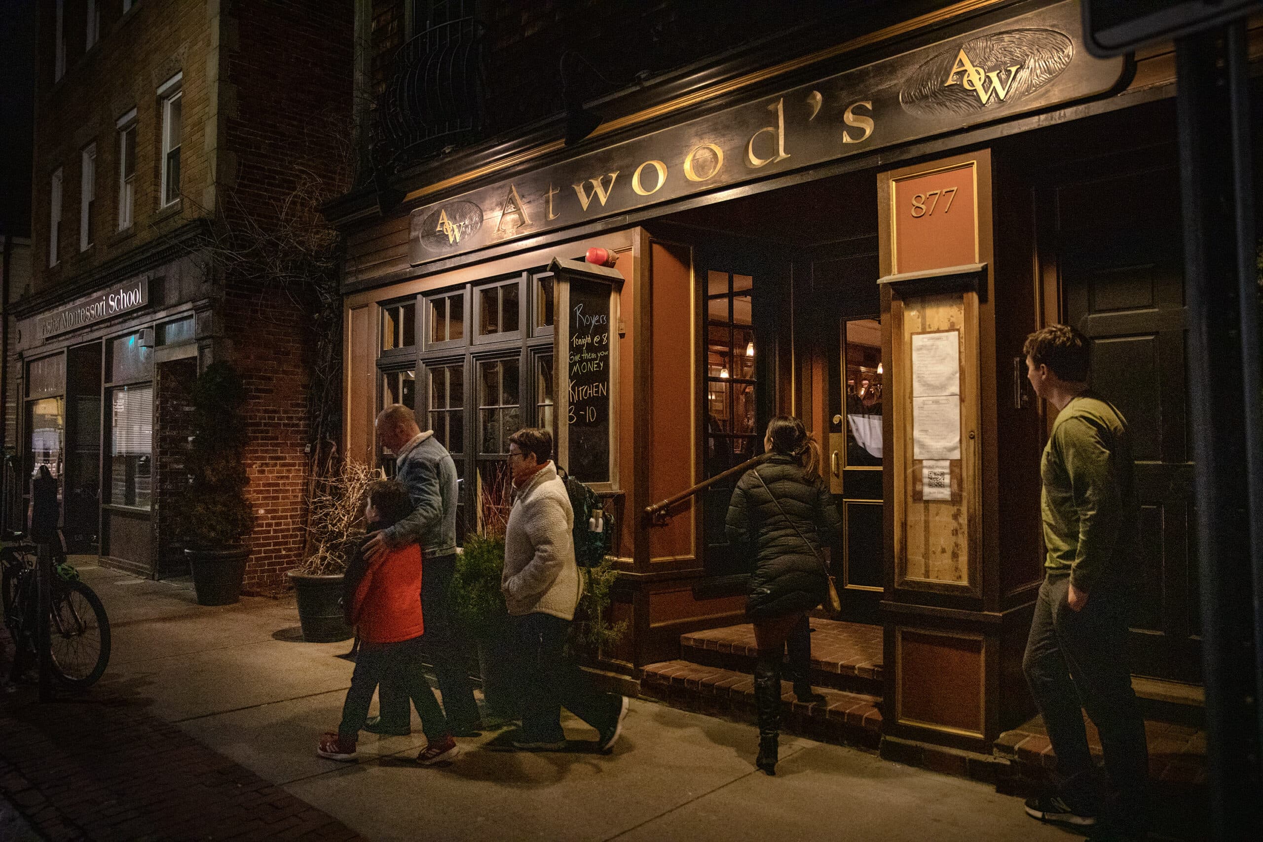 People entering and leaving Atwood's Tavern on Cambridge Street in Cambridge, on a weekday evening. (Robin Lubbock/WBUR)