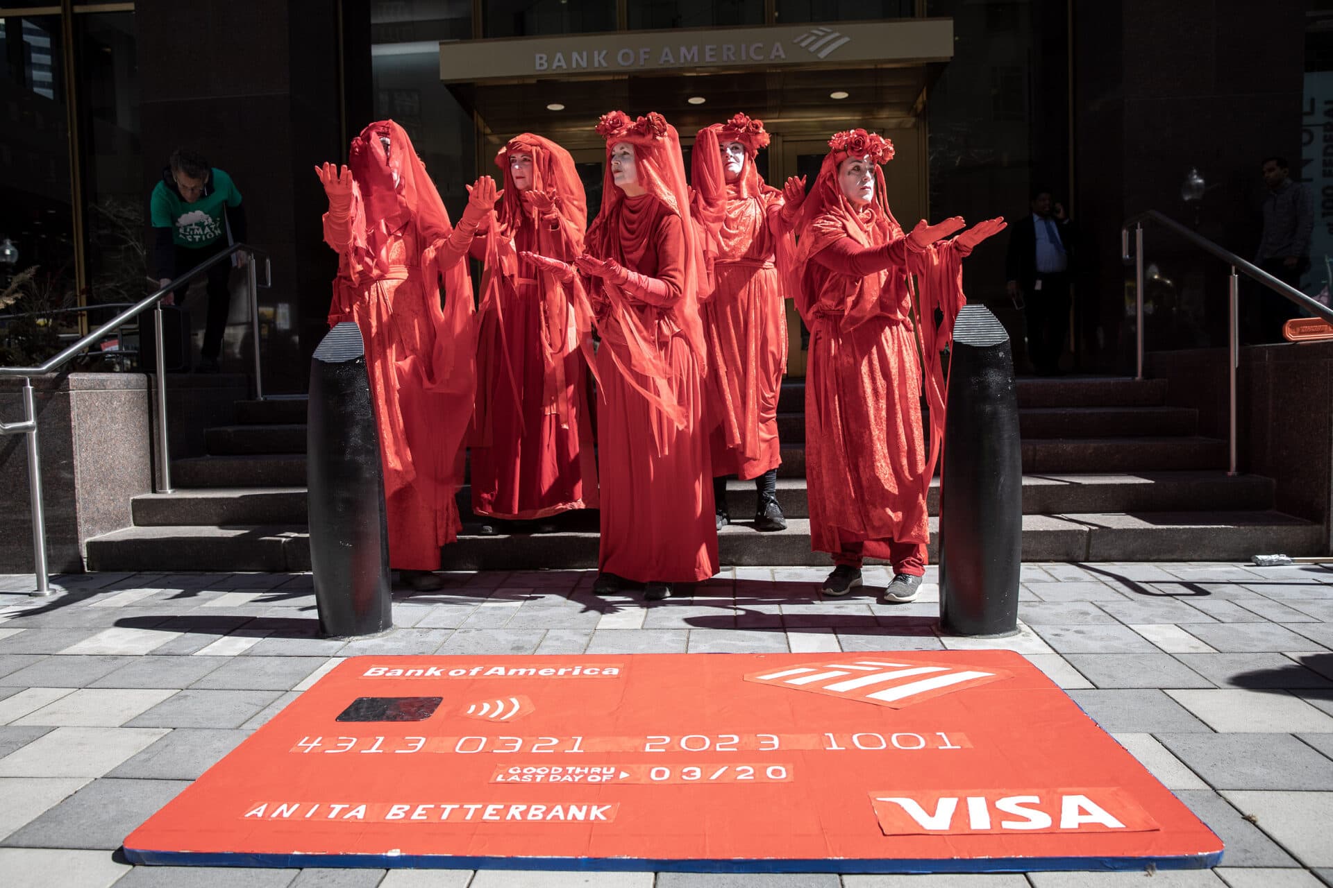 In front of Bank of America in downtown Boston, the Red Rebel Brigade dramatize sorrow, rage, hope and compassion as part of a protest against banks funding fossil fuel projects. (Credit: Robin Lubbock/WBUR)