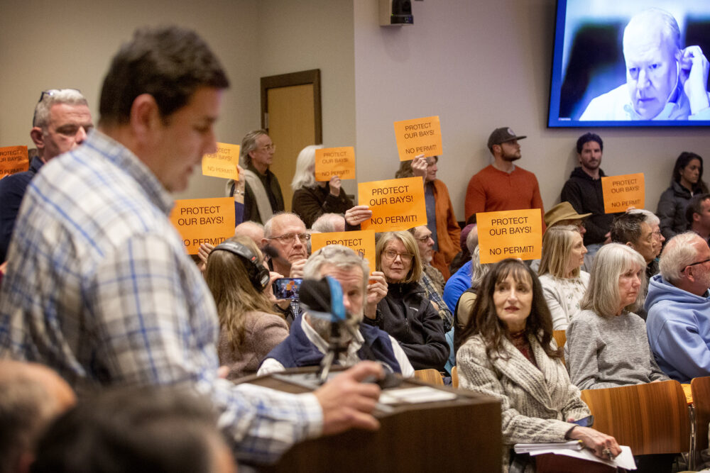 People attending the Nuclear Decommissioning Citizens Advisory Panel (NDCAP) meeting at Plymouth town hall, hold up signs saying 