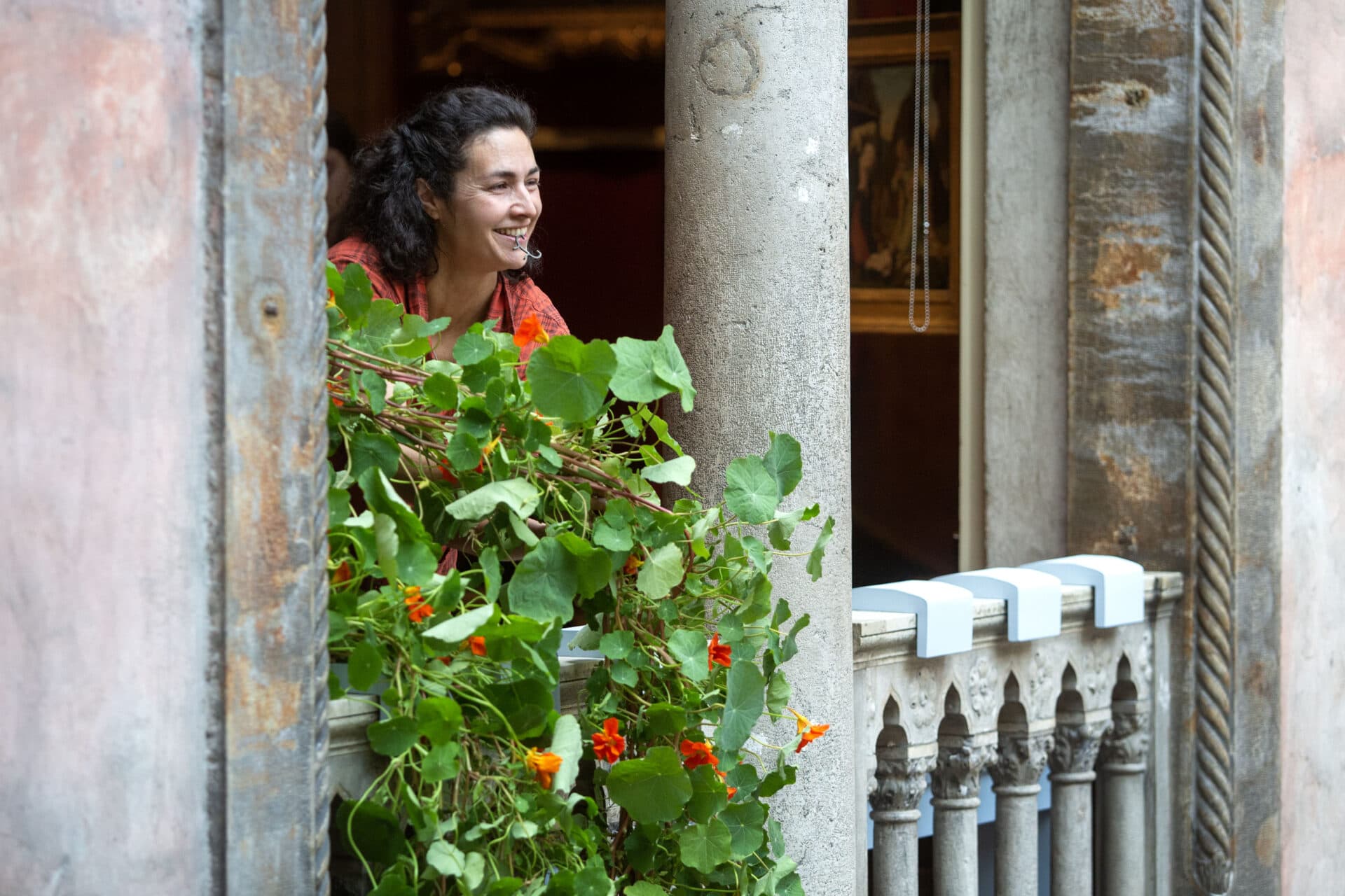 Horticulture Director Erika Rumbley carefully lowers nasturtiums out of a window into the courtyard of the Isabella Stewart Gardner Museum. (Robin Lubbock/WBUR)