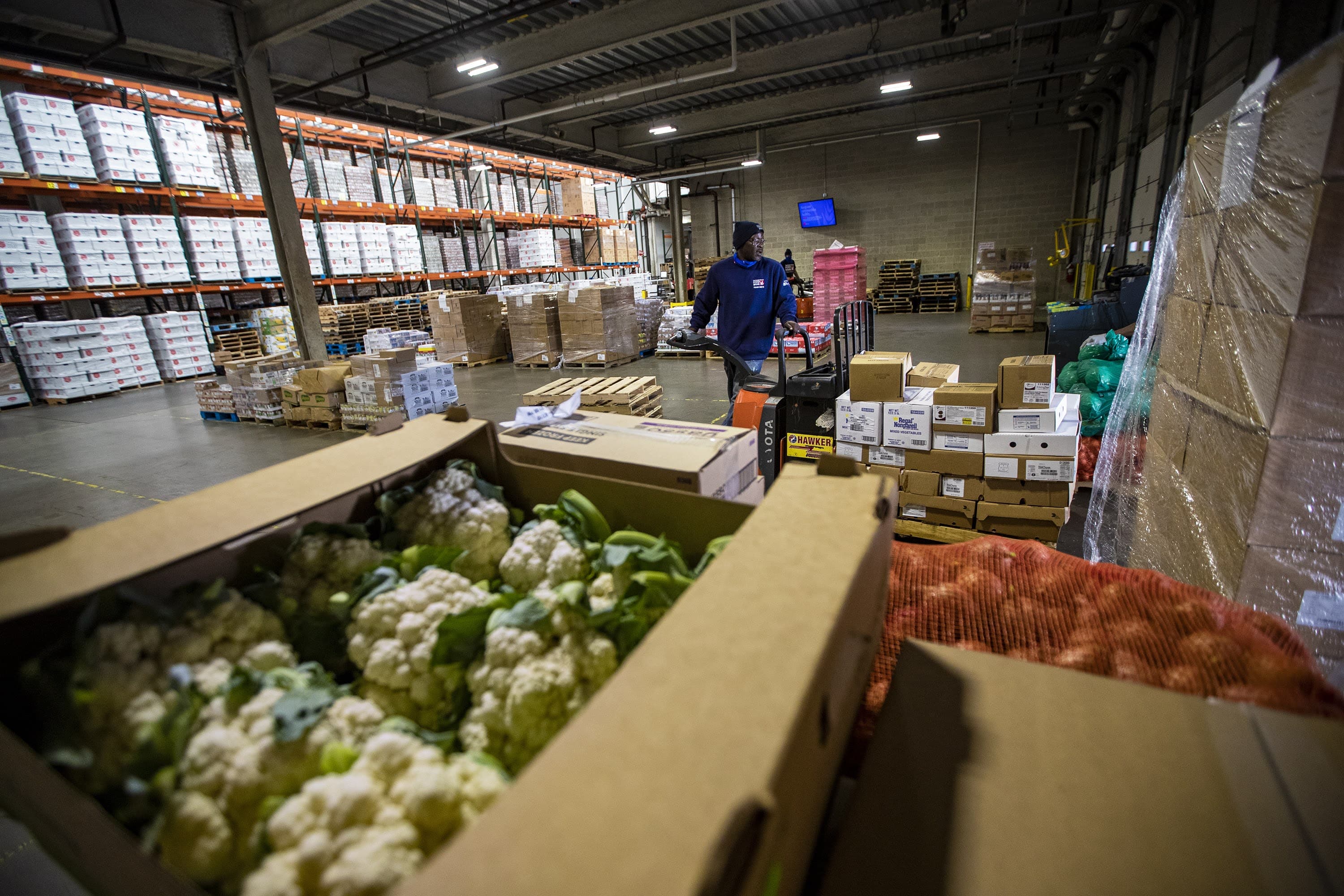 In this 2020 photo, Greater Boston Food Bank warehouse associates move pallets of food to the loading dock to be distributed around the Greater Boston area. (Jesse Costa/WBUR)