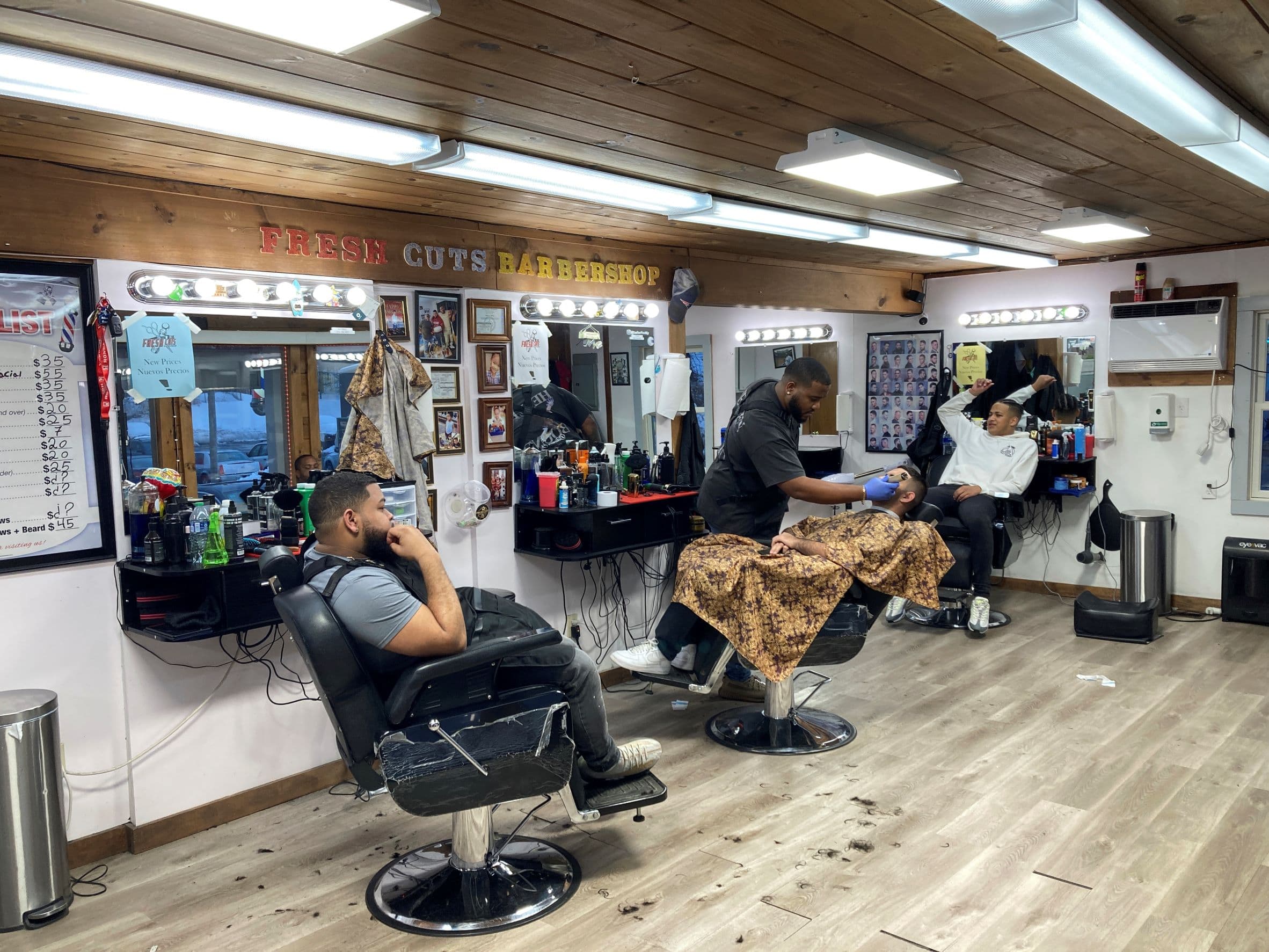 People get haircuts on March 15, at a barbershop where a man recently caused a disturbance in Leominster, Mass. (Michael Casey/AP)