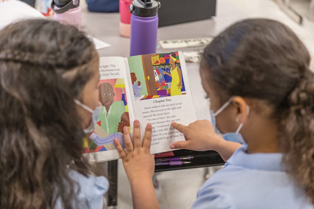 Two girls read a book together. (Jon Cherry/Getty Images)