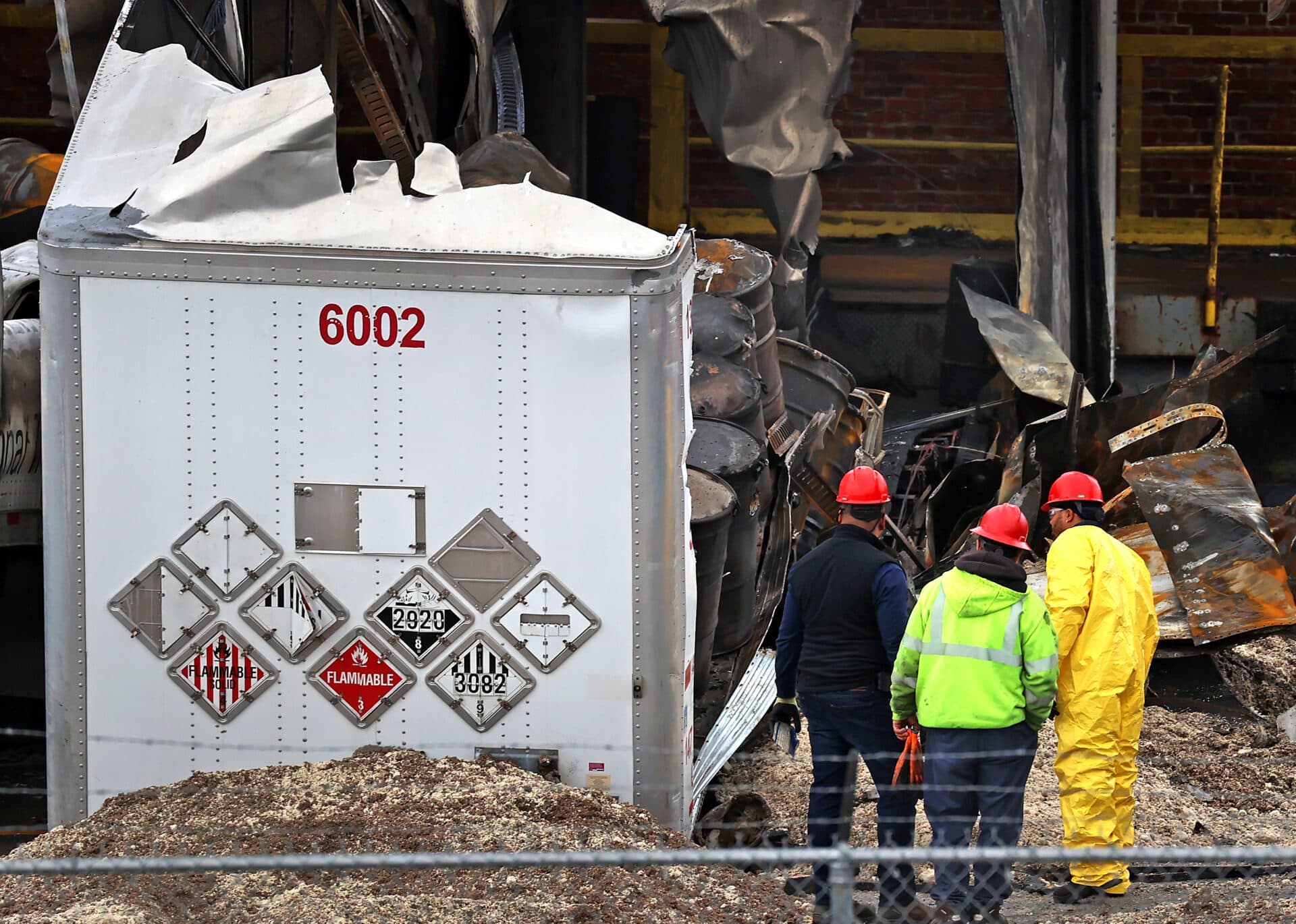 A work crew looks over a trailer marked with warning signs and barrels inside after a fire at Clean Harbors in Braintree. (David L. Ryan/The Boston Globe via Getty Images)