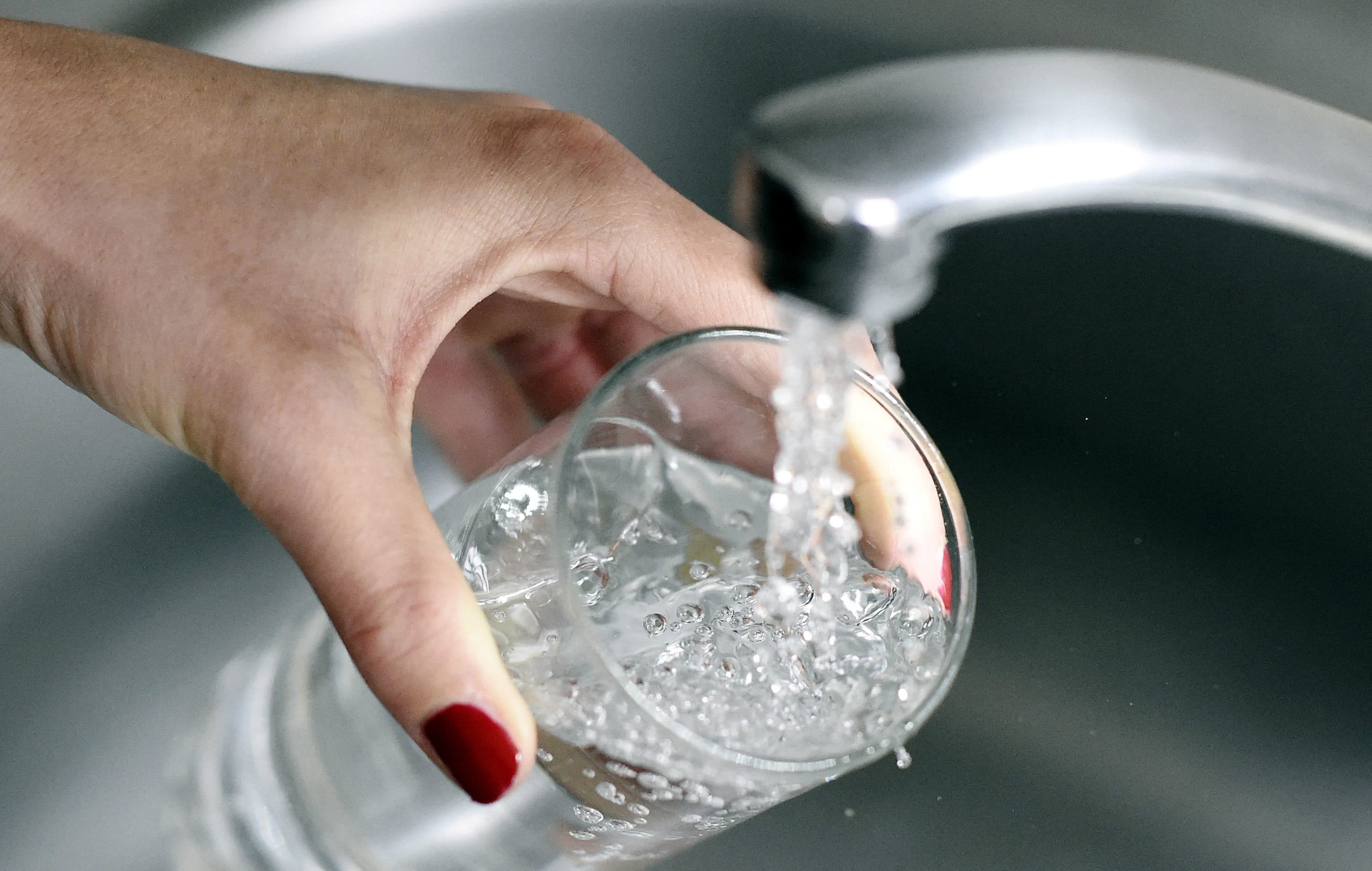 A woman fills up a glass with water. (Franck Fife/AFP via Getty Images)