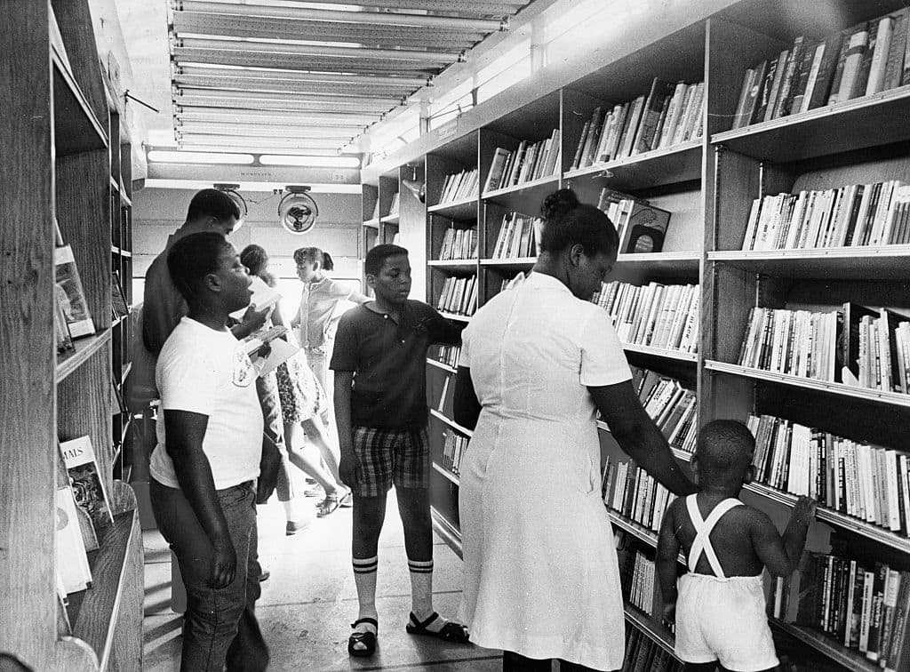 Children browse through shelves of books inside the Boston Public Library's Roxbury-North Dorchester bookmobile while it is parked at Columbia Road and Washington Street in Boston on July 26, 1968. The four mobile libraries that travel all over the city aim to make the library accessible to anyone. (Photo by Joe Dennehy/The Boston Globe via Getty Images)