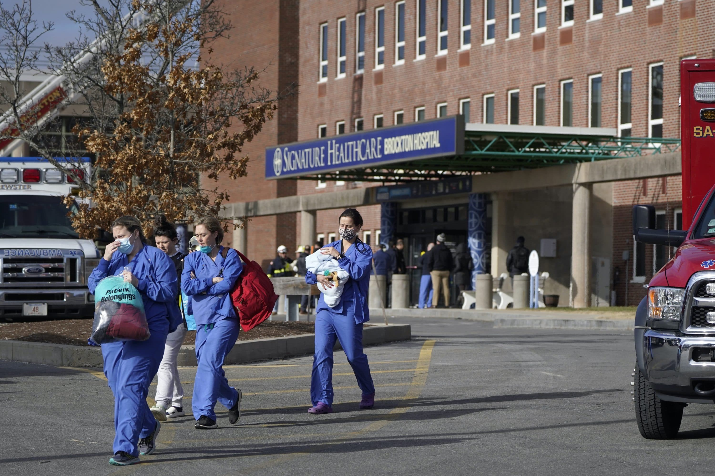 Medical staff walk away from an entrance to Signature Healthcare Brockton Hospital, Feb. 7, 2023, in Brockton. (Steven Senne/AP)
