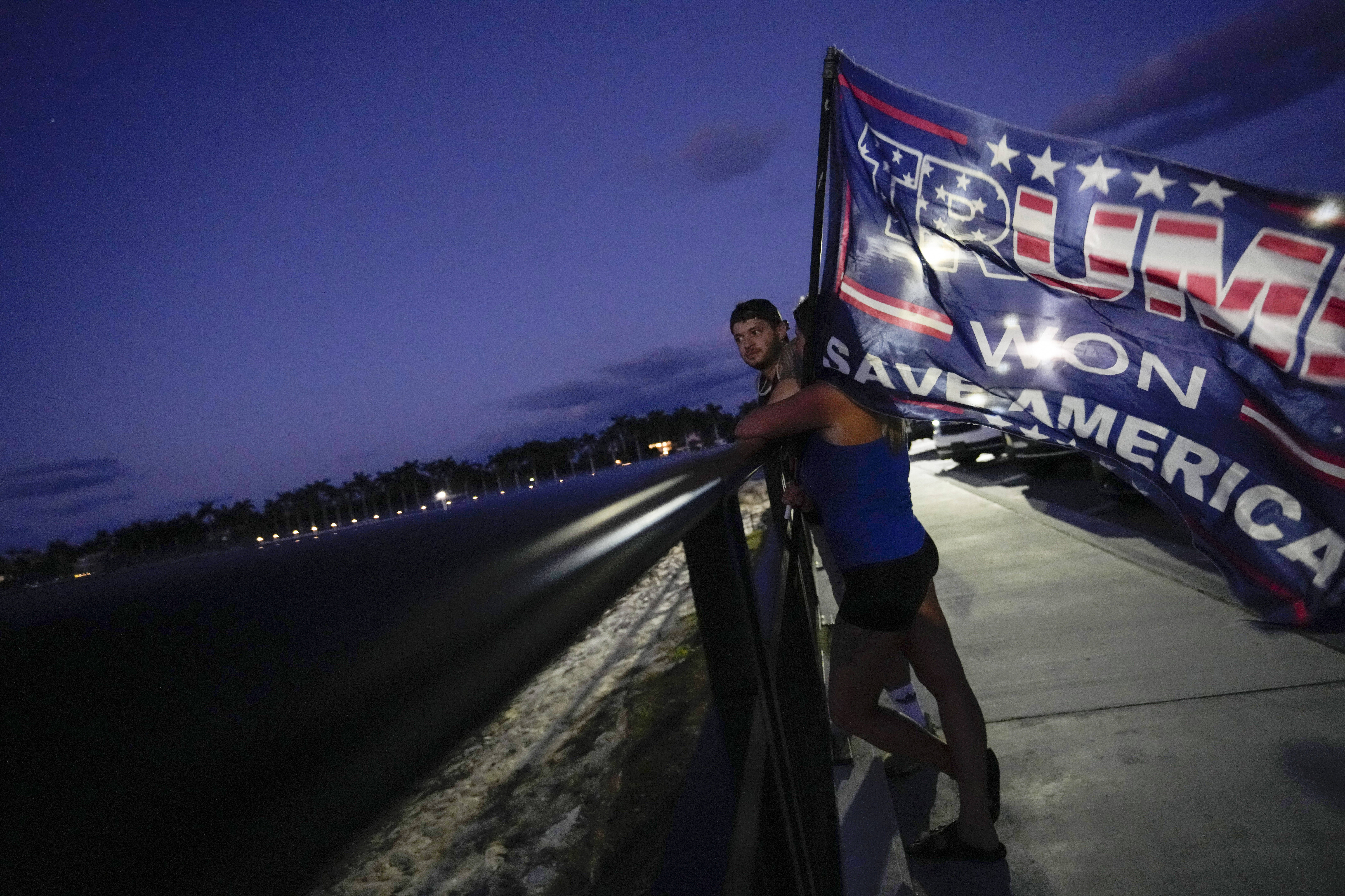 People hold a flag to show their support for former President Donald Trump following the news that Trump has been indicted by a Manhattan grand jury, March 30, near Trump's Mar-a-Lago estate in Palm Beach, Fla. (Rebecca Blackwell/AP)