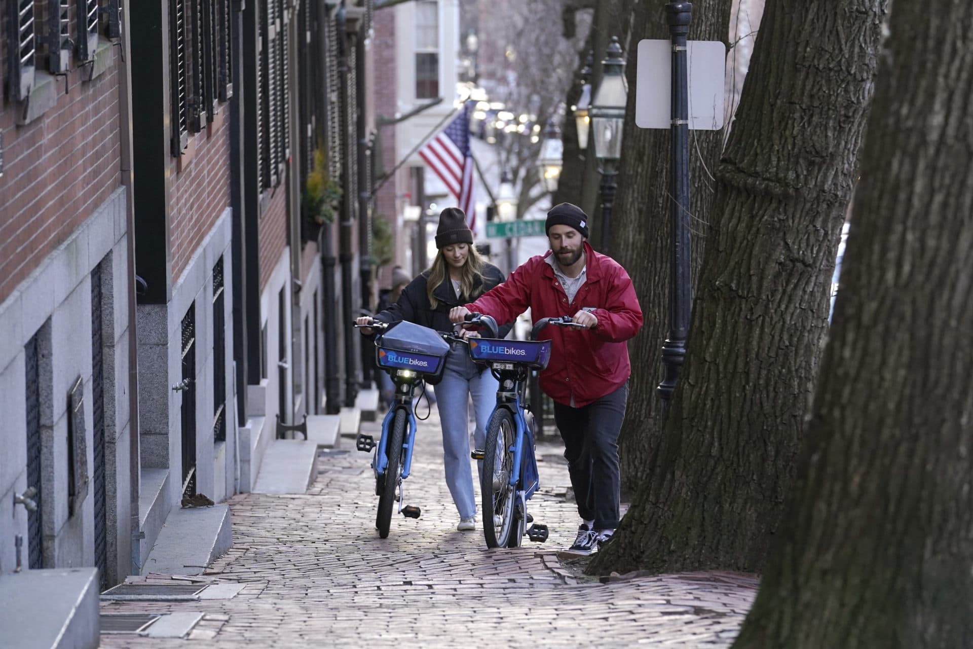 Passers-by walk their bikes up a hill in a residential area near the Statehouse on Beacon Hill, Feb. 13, in Boston.(Steven Senne/AP)