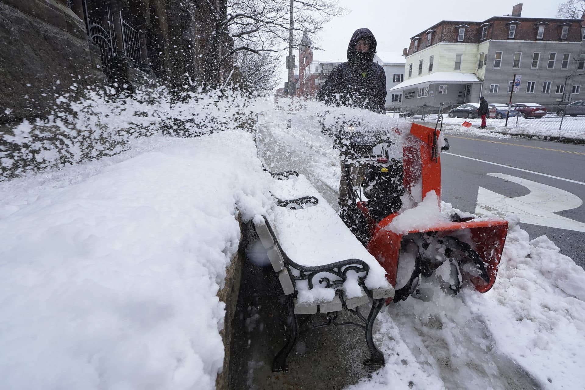 Joe Senckowski, of Oakham, Mass., uses a snow blower to remove snow from a sidewalk near All Saints Church, left in Worcester, Mass. (Steven Senne/AP)