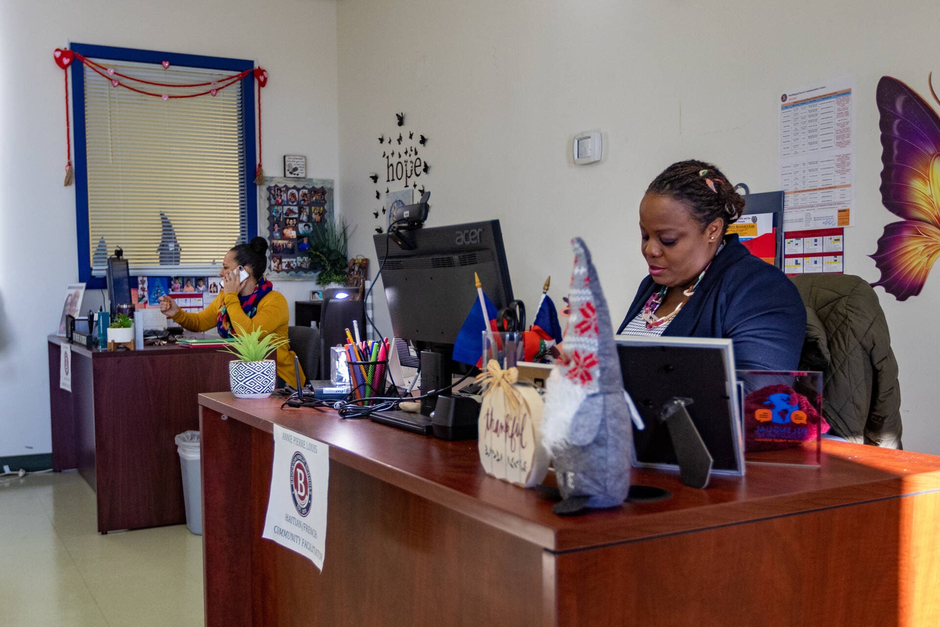 Lucia Alvarado, left, and Annie Pierre Louis field phone calls and return emails with questions from parents of children from Brockton Public Schools at the Brockton Public Schools Multilingual Parent Communication Center. (Jesse Costa/WBUR)