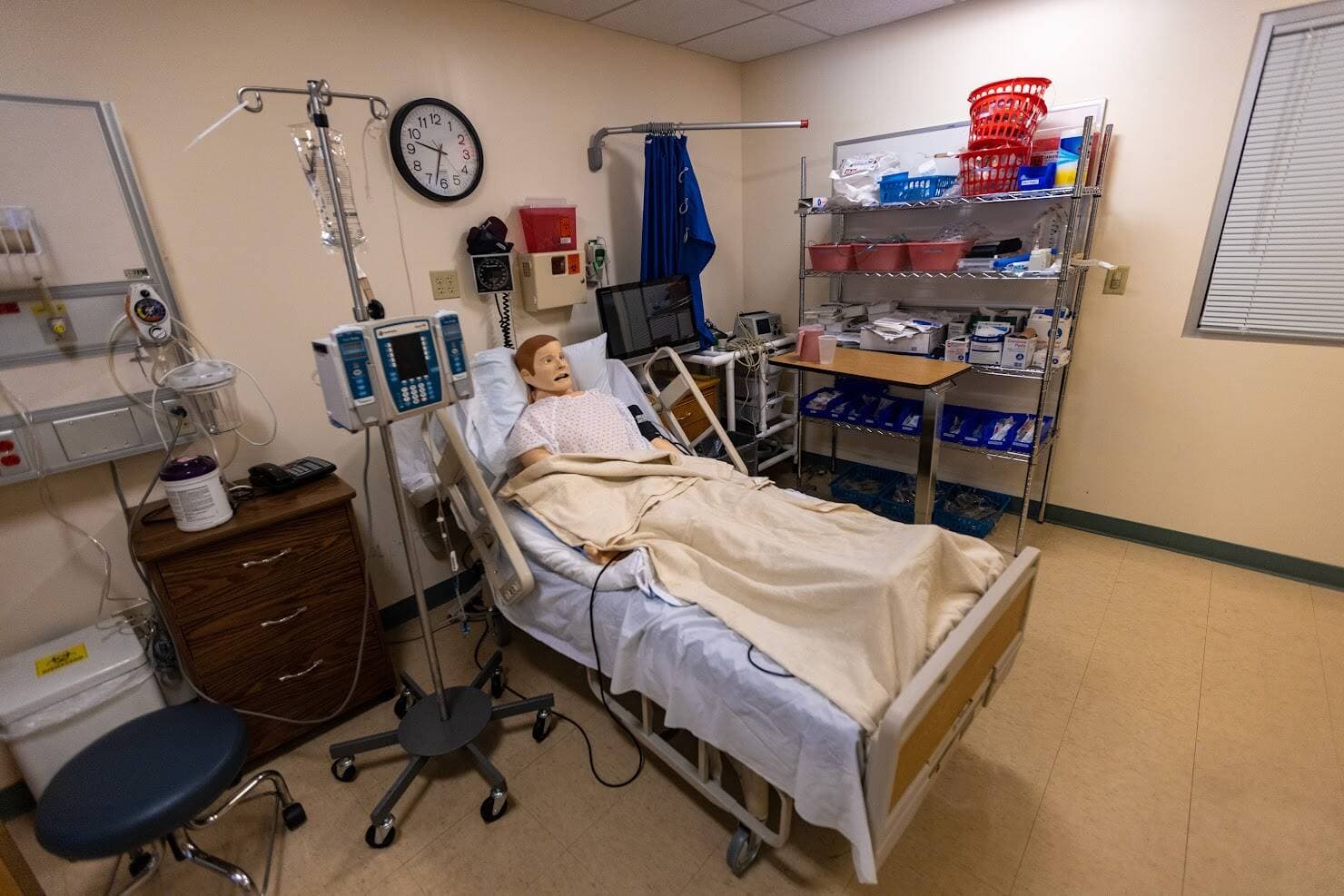 A training dummy lying in a bed in the Nursing Simulation Lab at Bay State College. (Jesse Costa/WBUR)