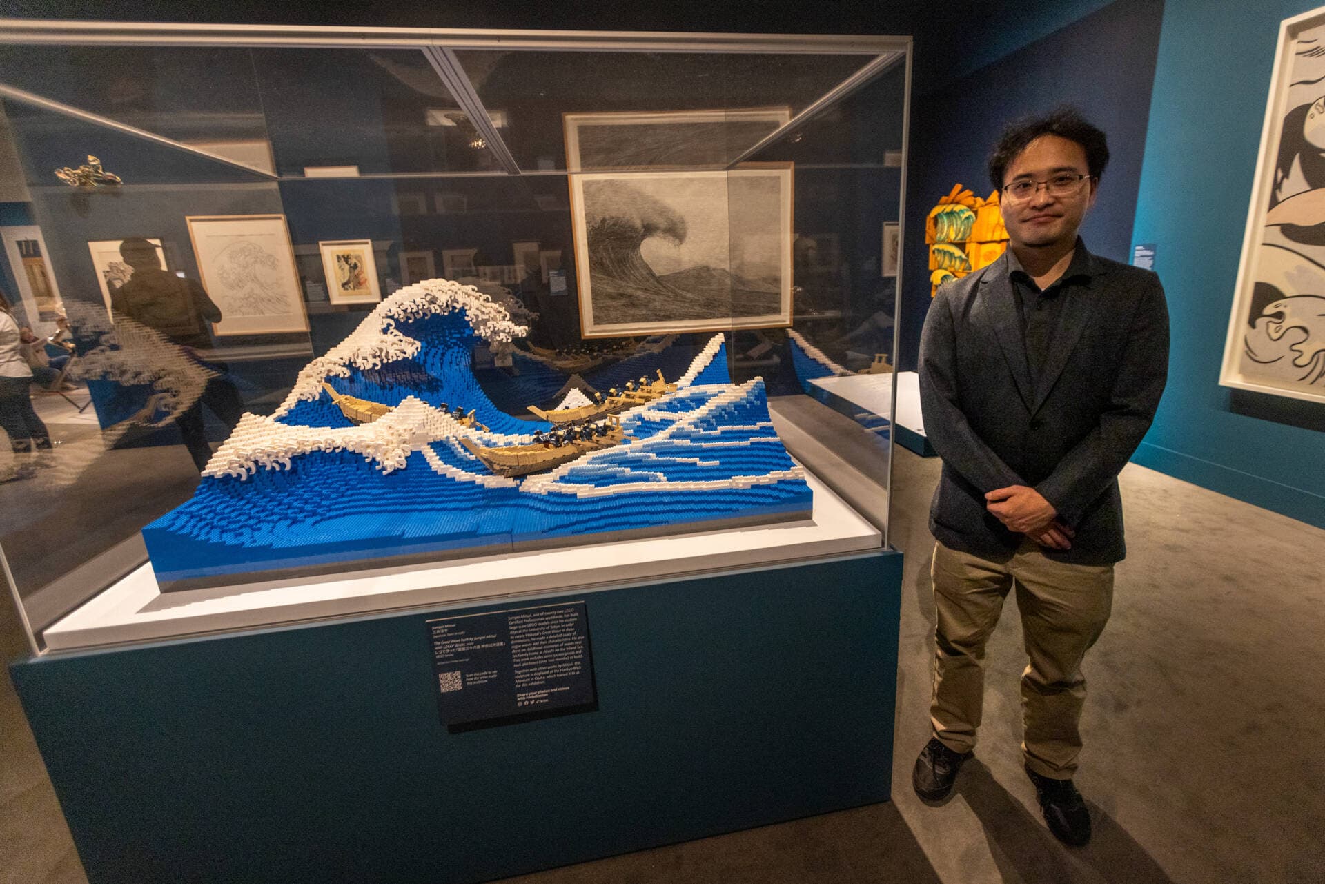 Artist Jumpei Mitsui stands with his 50,000 Lego block piece “The Great Wave built by Jumpei Mitsui with Lego Blocks” showing at the Museum of Fine Arts, Boston. (Jesse Costa/WBUR)