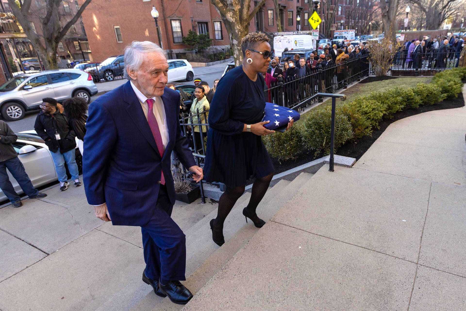 U.S. Senator Edward Markey and Nika Elugardo walk up the stairs Union United Methodist Church with an American Flag which was flown over the U.S. Capitol in remembrance of the late Mel King. (Jesse Costa/WBUR)