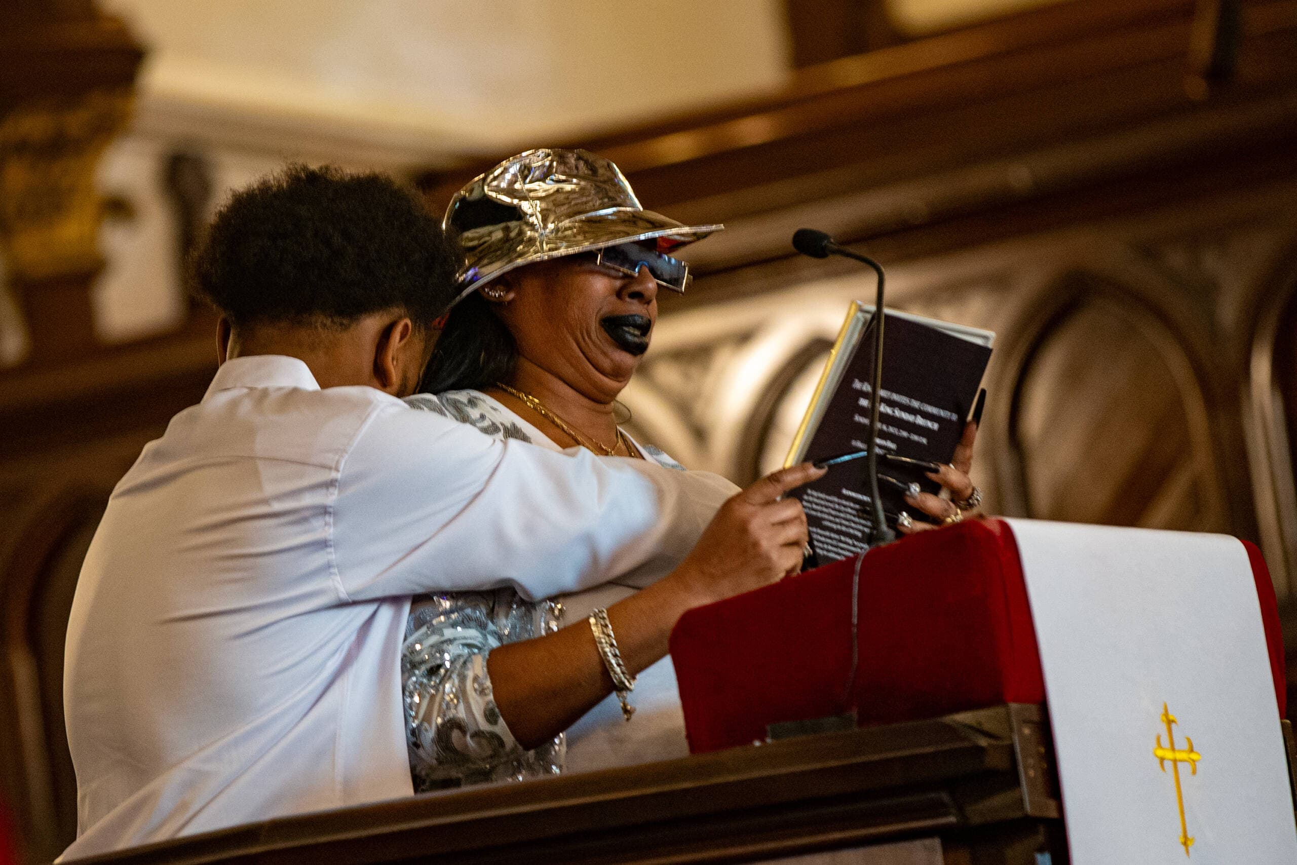 Nancy King is embraced by her son as she cries during her remembrance of her father Mel King. (Jesse Costa/WBUR)