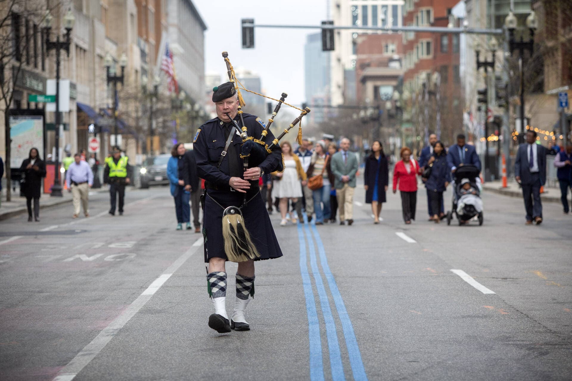 A bagpiper leads Gov. Maura Healey and Mayor Michelle Wu along Boylston Street at a remembrance with families who lost loved ones at the 2013 Boston Marathon bombings. (Robin Lubbock/WBUR)