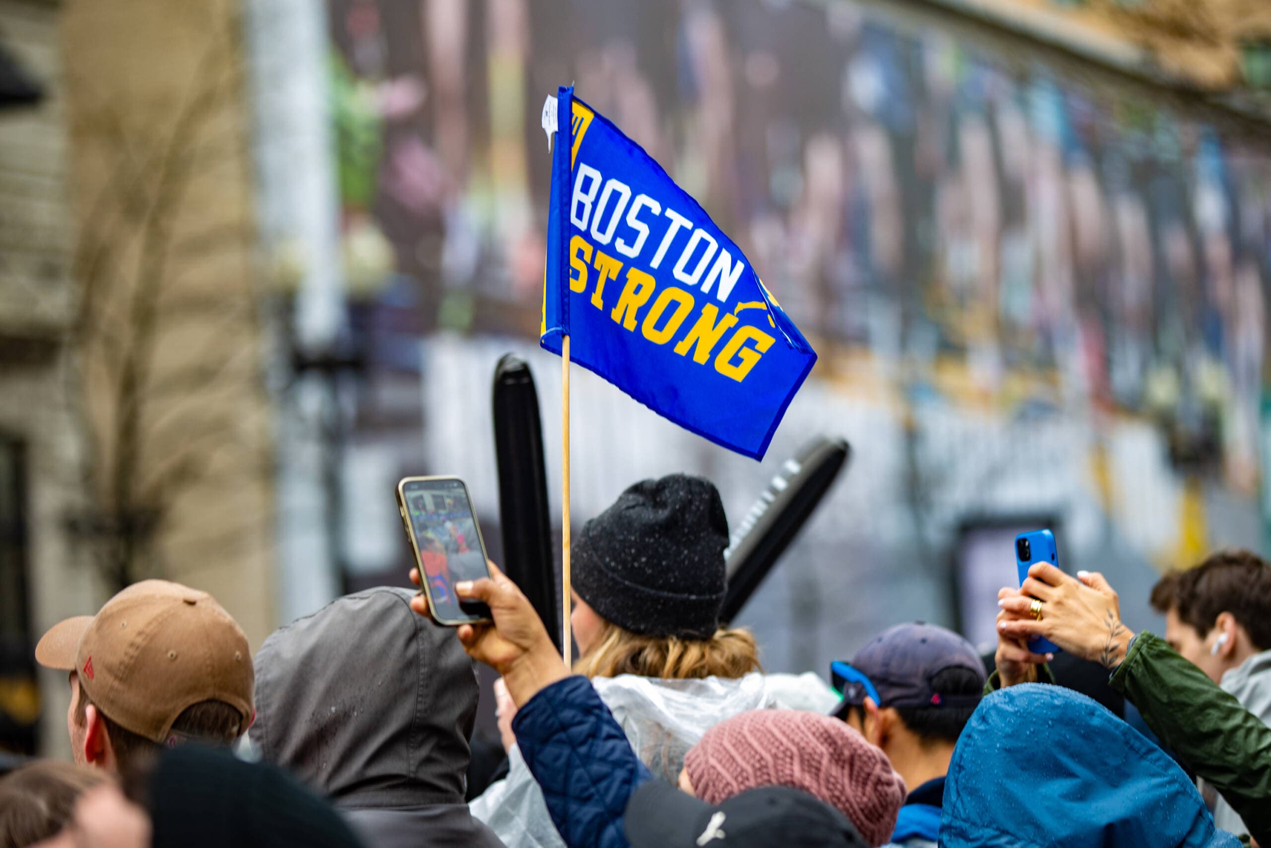 A spectator waves a Boston Strong flag on Boylston Street as a wheelchair racer approaches the finish line. (Jesse Costa/WBUR)