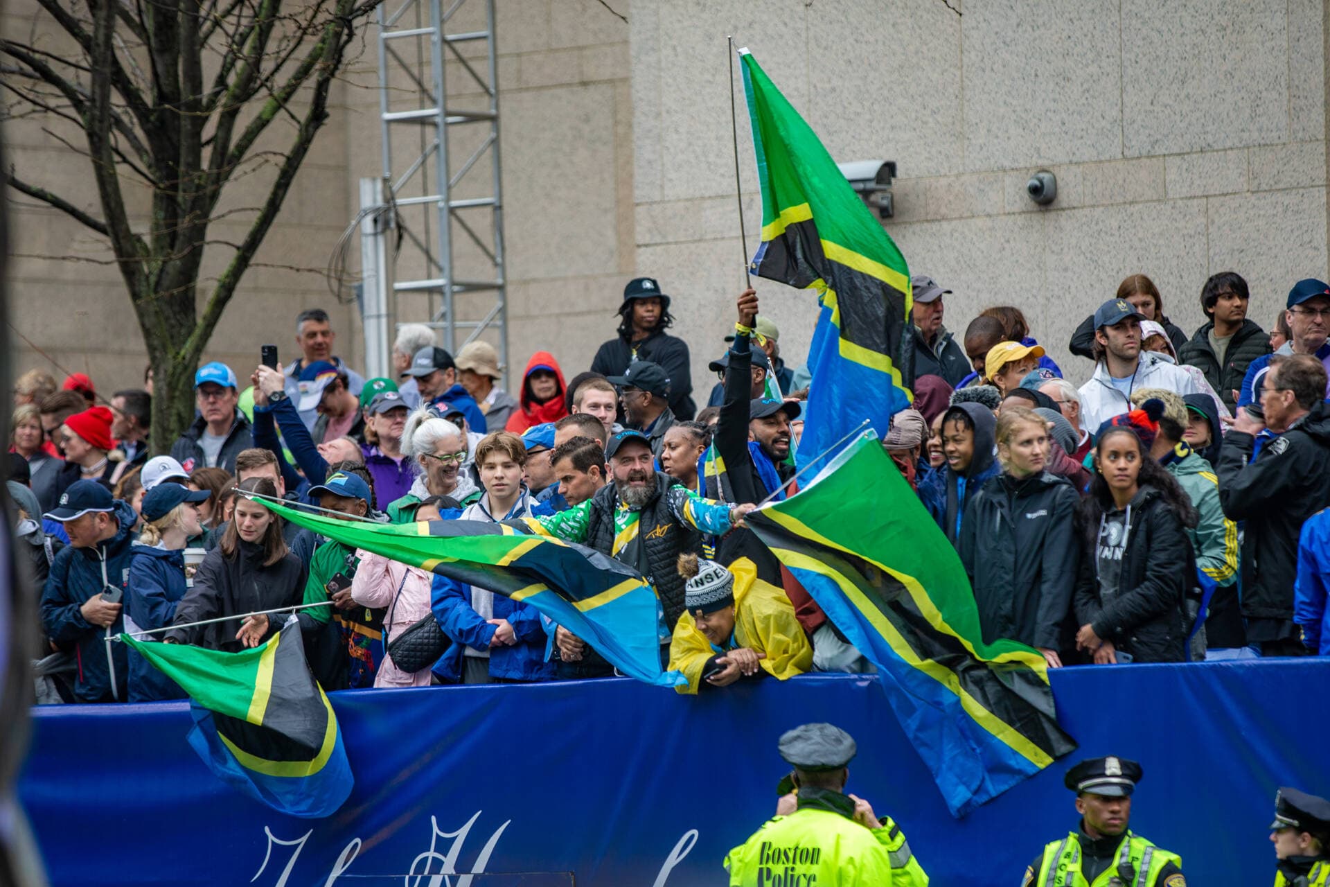 Spectators in the grandstand wave Tanzanian flags as the elite men’s racers approach the finish line on Boylston Street. (Jesse Costa/WBUR)
