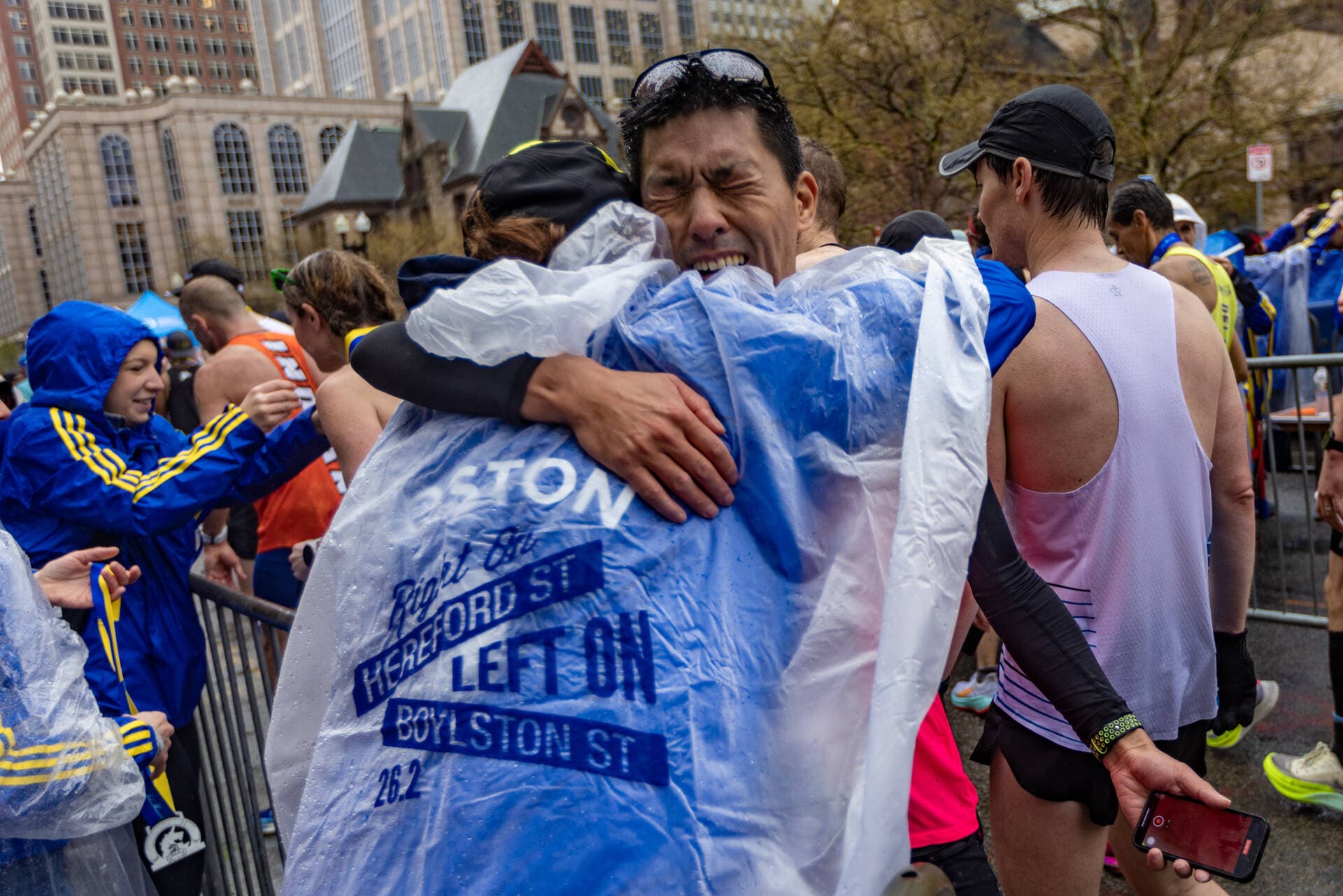 Henry To, of Australia, embraces a medal presenter after he finished running the Boston Marathon. (Jesse Costa/WBUR)