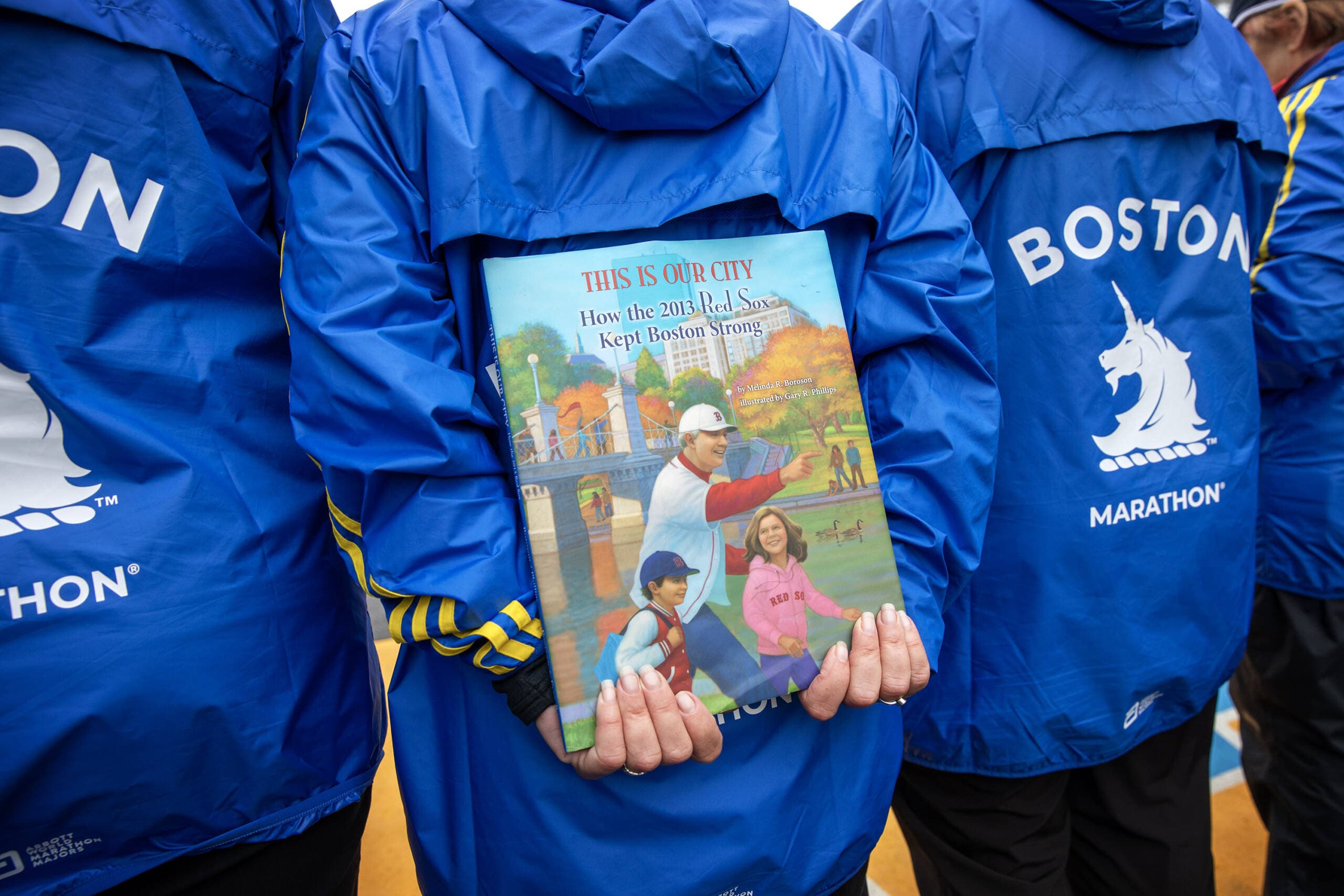 A B.A.A. course official holds a copy of "This Is Our City: How the 2013 Red Sox Kept Boston Strong." (Robin Lubbock/WBUR)