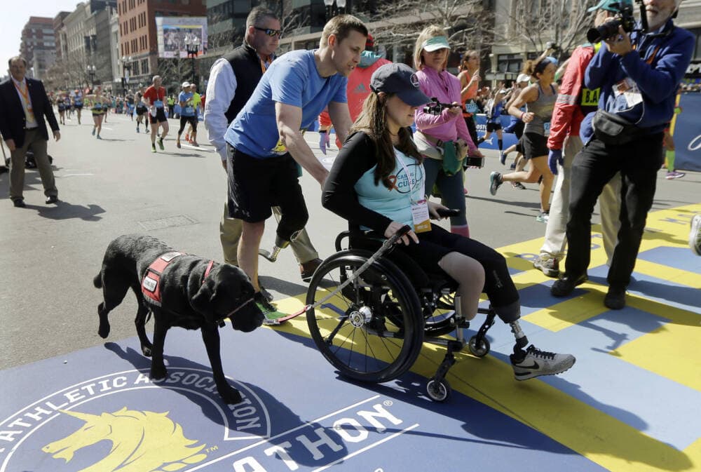 Boston Marathon bombing survivor Patrick Downes pushes his wife Jessica across the finish line after he finished the 120th Boston Marathon on April 18, 2016. (Elise Amendola/AP)