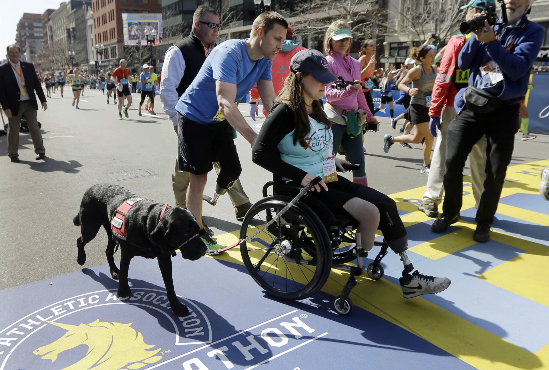 Boston Marathon bombings survivor Patrick Downes pushes his wife, Jessica Kensky, across the finish line after he finished the 120th Boston Marathon on Monday, April 18, 2016, in Boston. (Elise Amendola/AP)