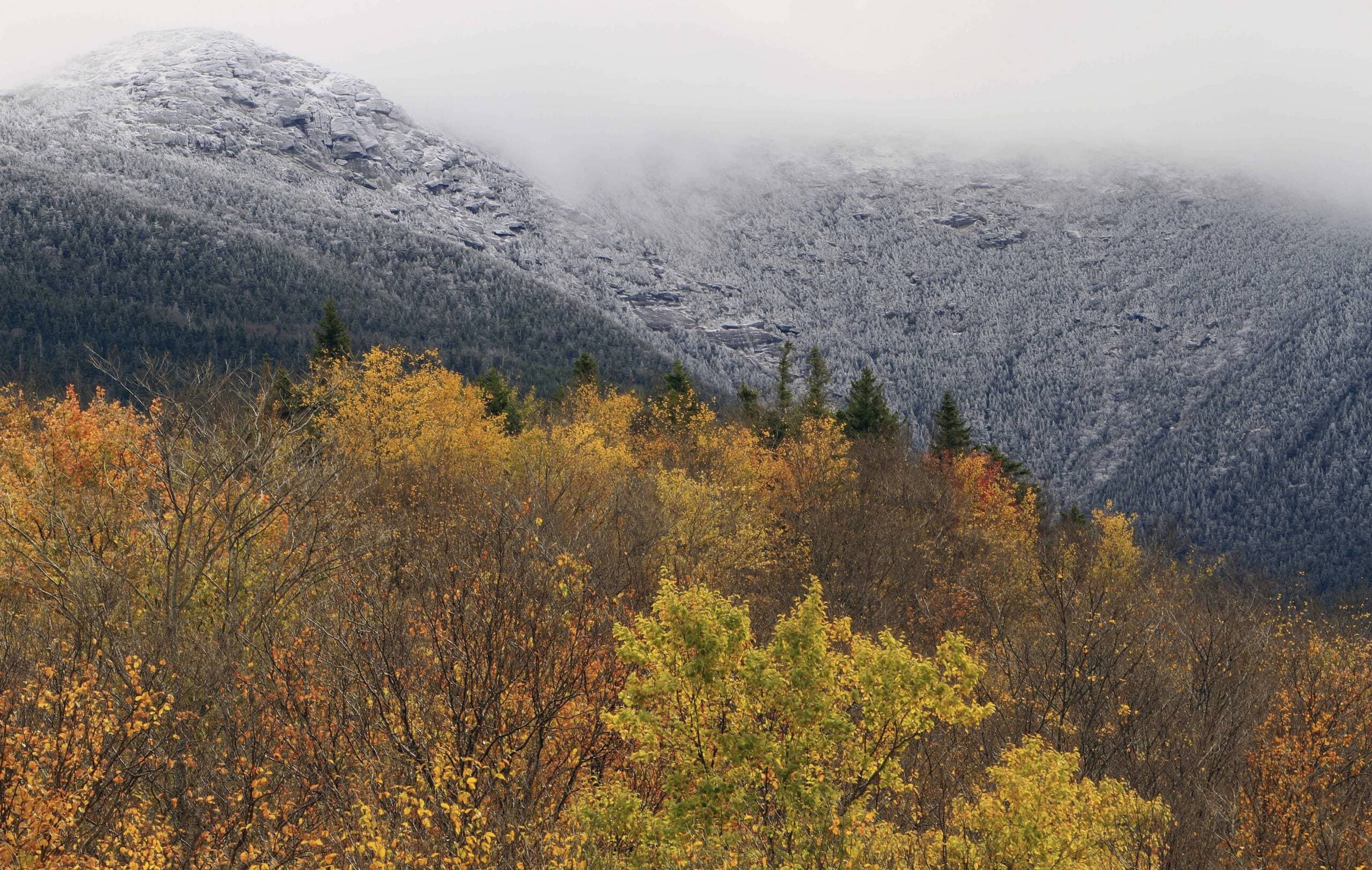 Morning clouds lift off the snow covered summit of Mount Lafayette as the sun hits the colorful leaves, Thursday, Oct. 11, 2012 in Franconia, N.H. Officials said Emily Sotelo died when she was caught unprepared in harsh conditions during a hike in November 2022. (Jim Cole/AP)