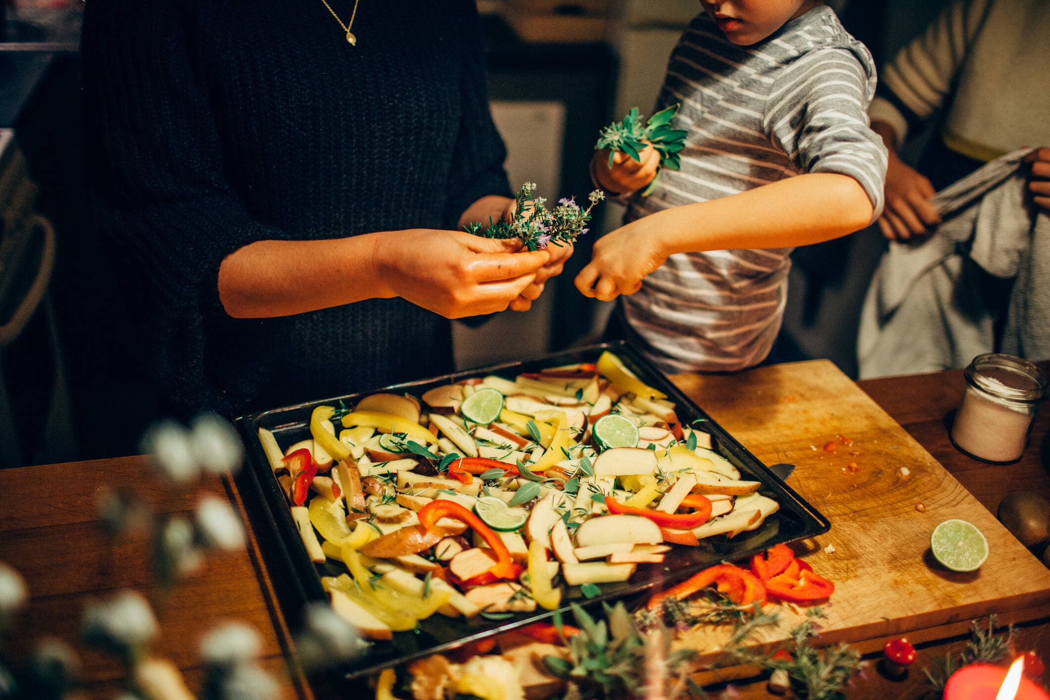 A young boy sprinkling fresh herbs on a vegetable dish. (Getty Images)