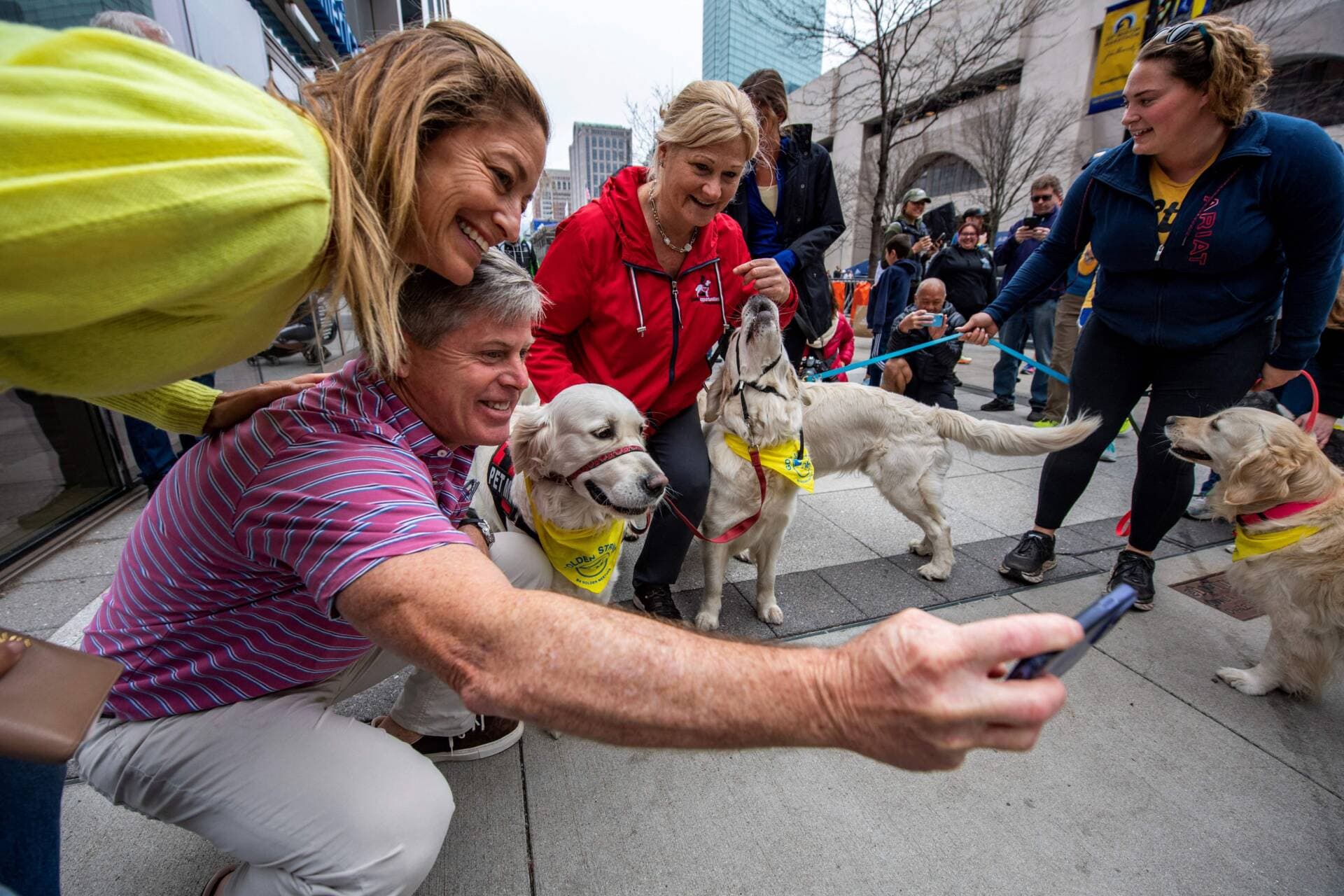 People take photos with dozens of golden retrievers, and their owners, as they stand by the Boston Marathon finish line in Boston, Massachusetts, on April 16, 2023. (Joseph Prezioso/AFP via Getty Images)