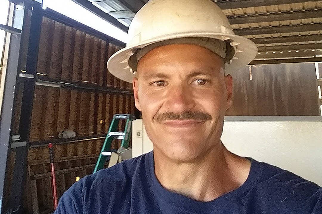Wideman, a multiracial man, wearing a construction hat. 