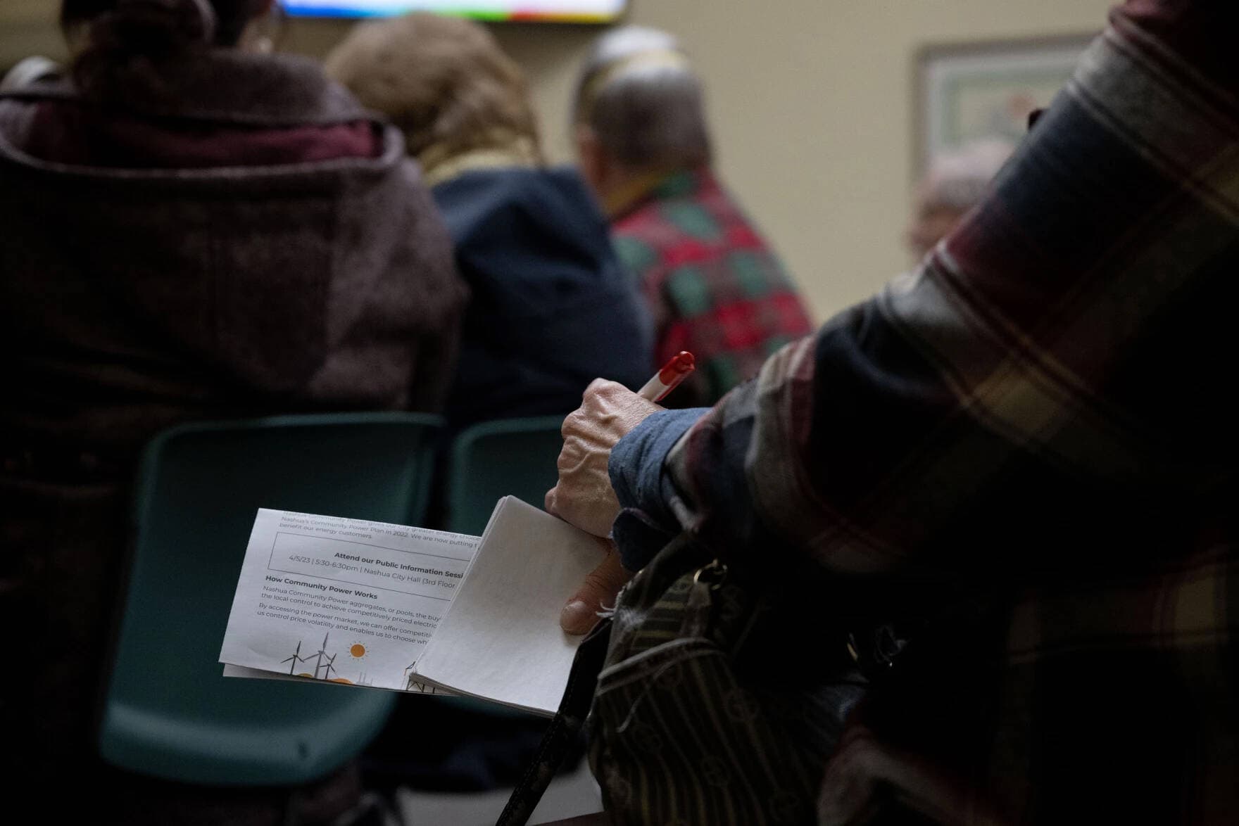 A community member holds an informational sheet on April 5, 2023, during a meeting about community power at City Hall in Nashua, N.H. (Raquel C. Zaldívar/New England News Collaborative)