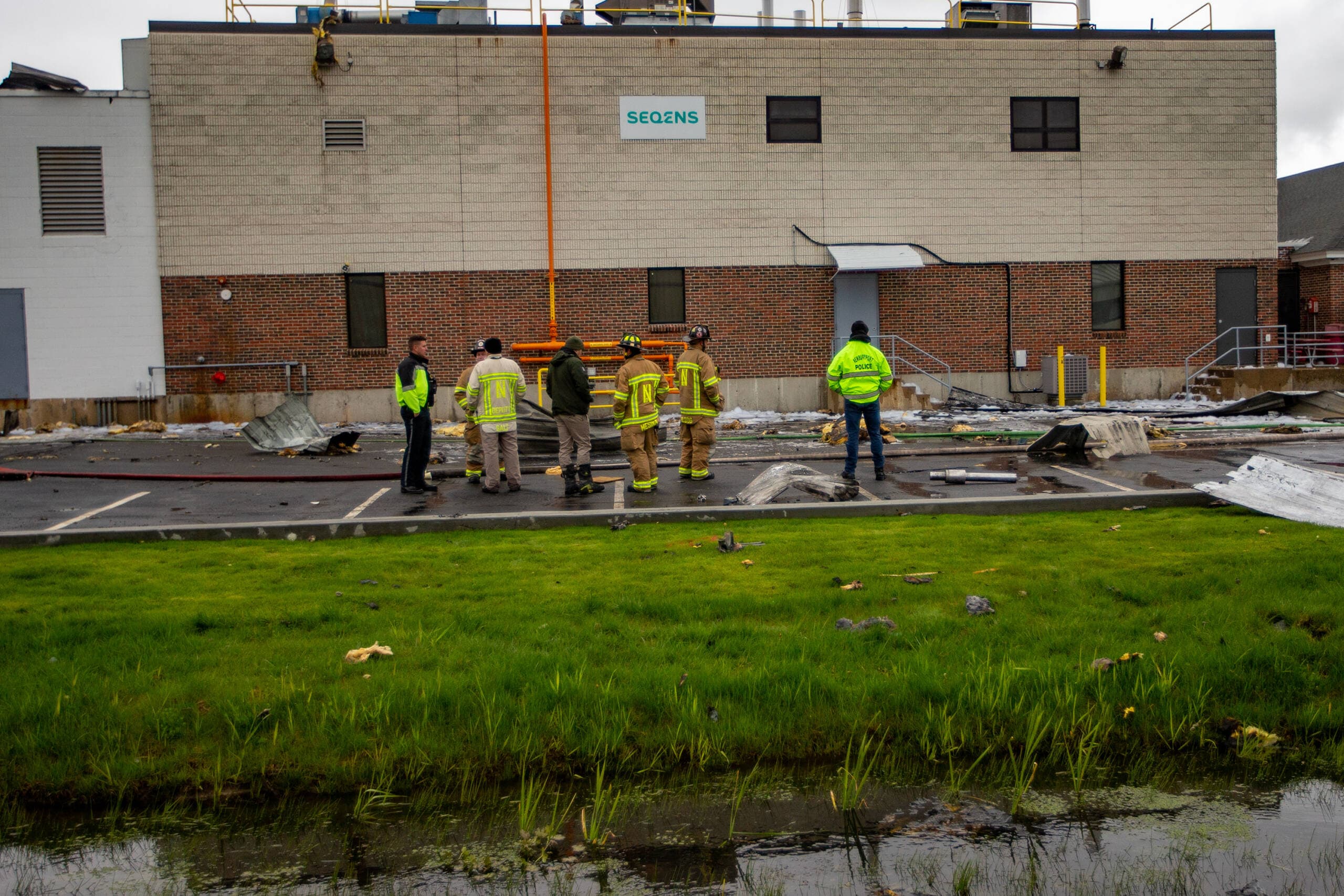Newburyport firefighters examine the debris around the Seqens/PCI Synthesis plant after a chemical explosion overnight. (Jesse Costa/WBUR)