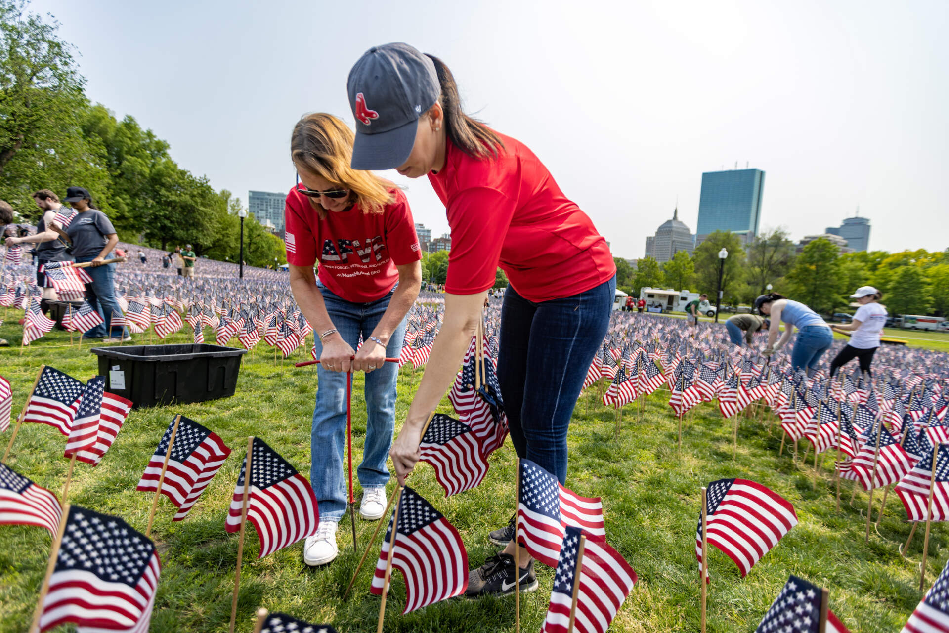 Volunteers Kim Bullock and Monique Carbonneau plant American flags into the ground of the Boston Common for the upcoming Memorial Day weekend. (Jesse Costa/WBUR)