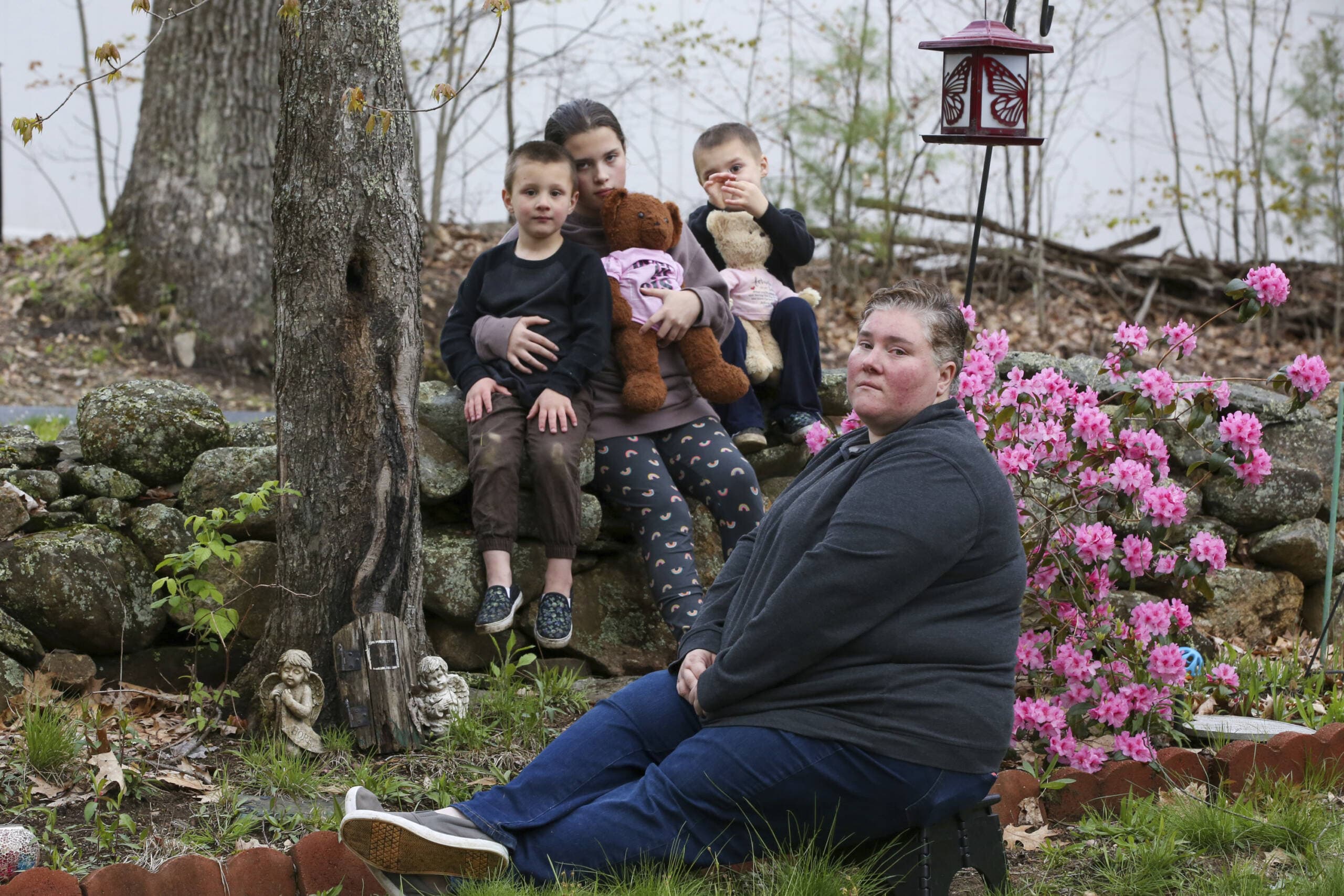 Jillian Philips poses with her children, Macy, 10, and 4-year old twins, Jude and Emmett, right, in a memorial garden at her home, Tuesday, May 2, 2023, in North Brookfield, Mass. The remains her 5 day old child Emilia and buried there along with remains of her 2016 miscarriage. (Reba Saldanha/AP)