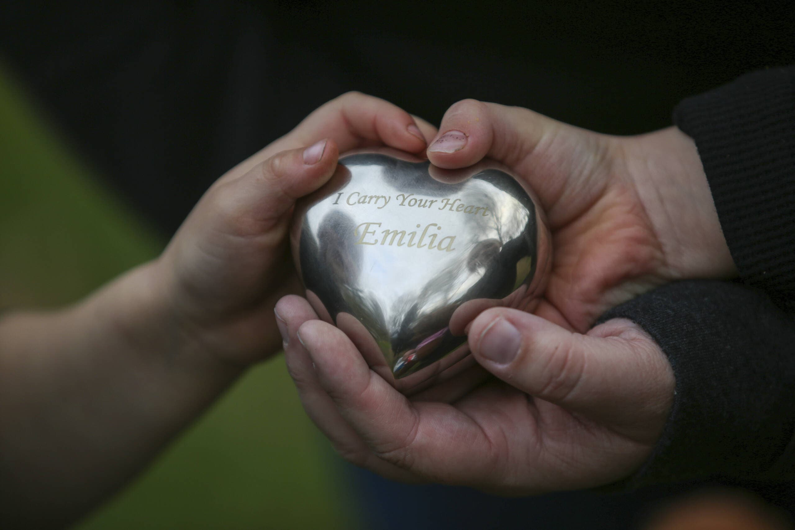Jillian Philips and her sons, Jude and Emmett, hold an urn containing some of the ashes of her daughter, Emilia Phillips, Tuesday, May 2, 2023, in North Brookfield, Mass. The urn is housed in a teddy bear that daughter Macy sleeps with nightly. (Reba Saldanha/AP)