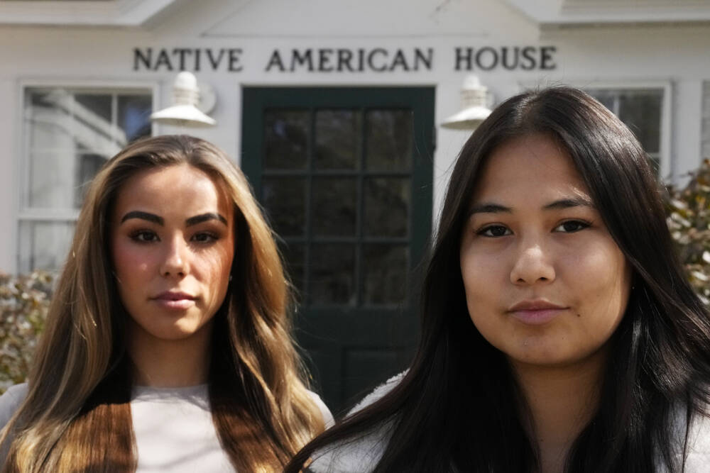 Dartmouth College students Marisa Joseph, right, a member of the Tulalip Tribes of Washington, poses with Ahnili Johnson-Jennings, left, a member of the Quapaw, Choctaw, Sac and Fox and Miami tribes, pose outside the Native American House at Dartmouth College, Friday, April 7, 2023, in Hanover, N.H. The college announced in March 2023 that it housed partial Native American skeletal remains in their collection. Dartmouth has set in motion an effort to repatriate the remains to the appropriate tribes. (Charles Krupa/AP)