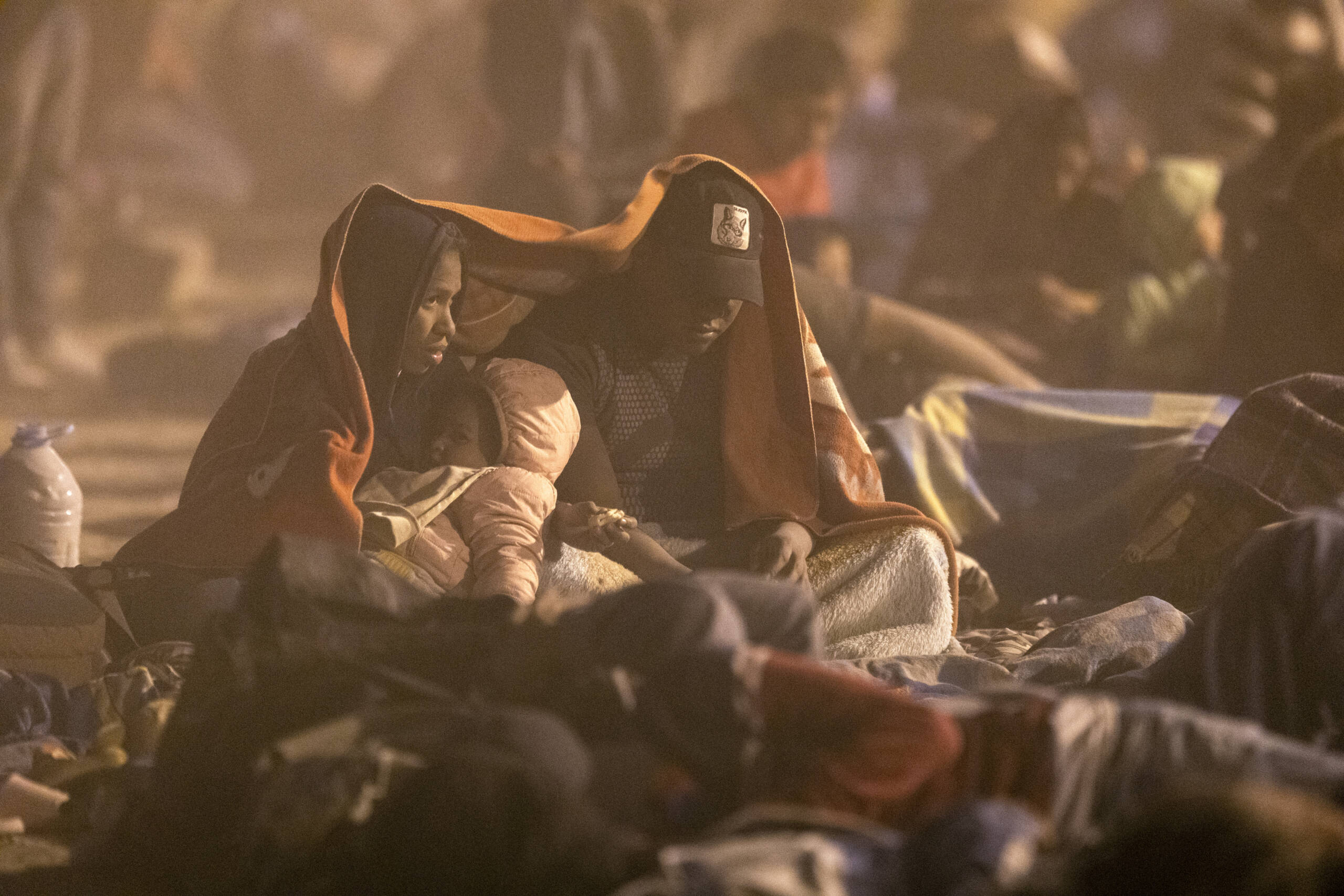Immigrants from Venezuela cover up during a dust storm at a makeshift immigrant camp located between the Rio Grande and the U.S.-Mexico border fence on May 10, 2023 in El Paso, Texas. (John Moore/Getty Images)