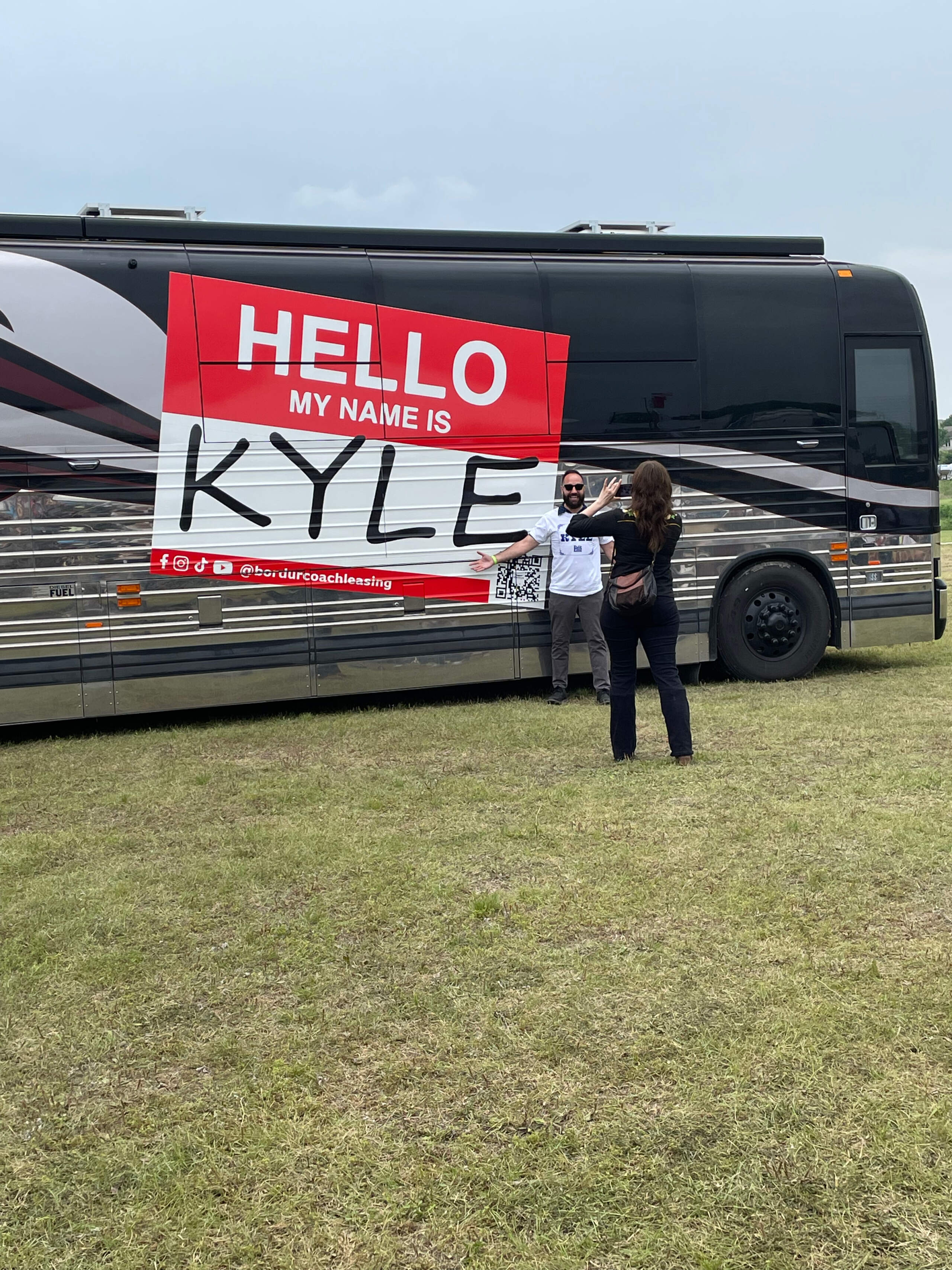 One of the many people named Kyle at the recent Kyle Fair in Kyle, Texas, stands in front of a Kyle bus. (Kyle Gassiott/Troy Public Radio)