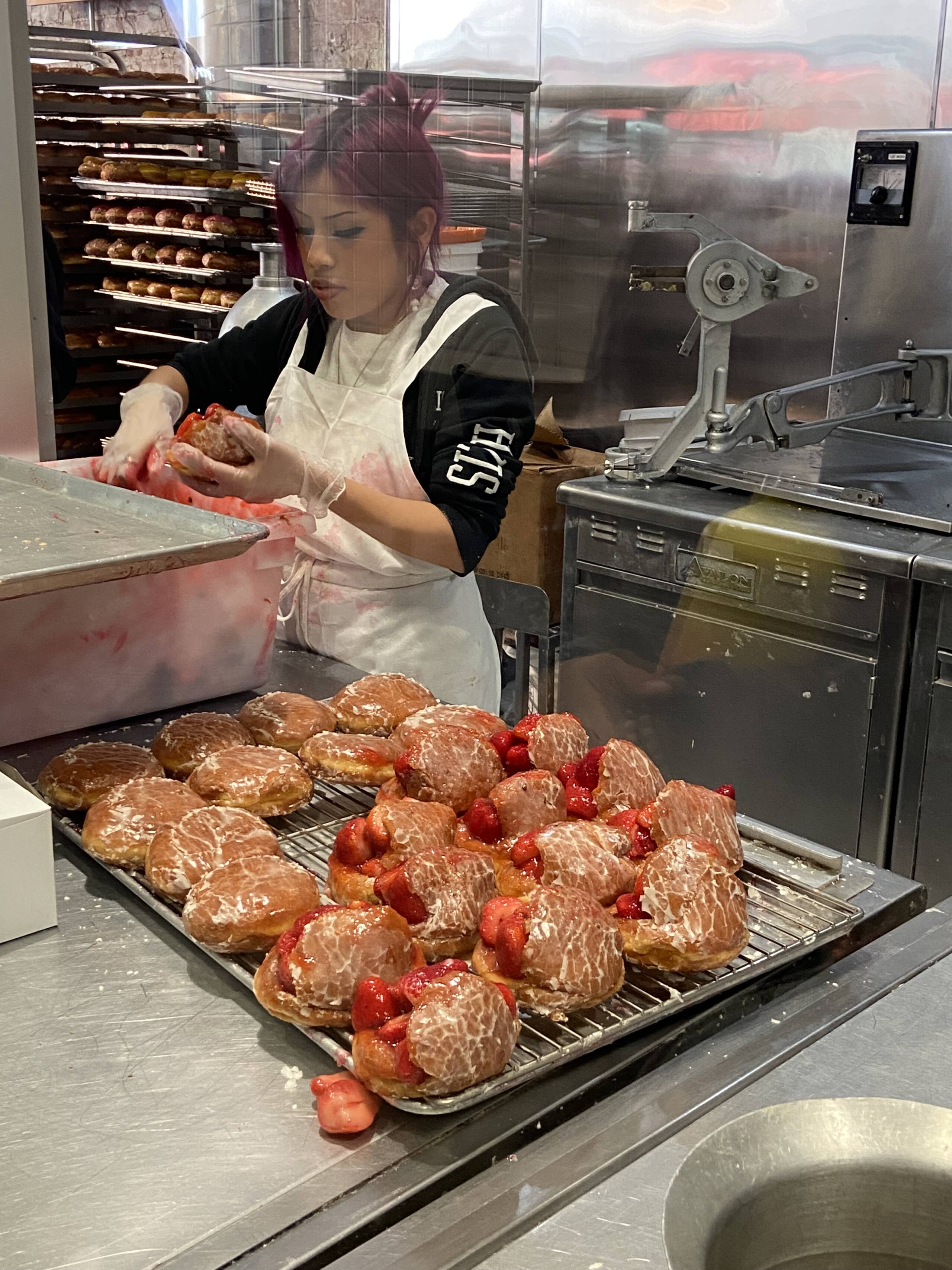 A woman stuffs donuts full of cream and strawberries at The Donut Man. (Kathy Gunst/Here & Now)