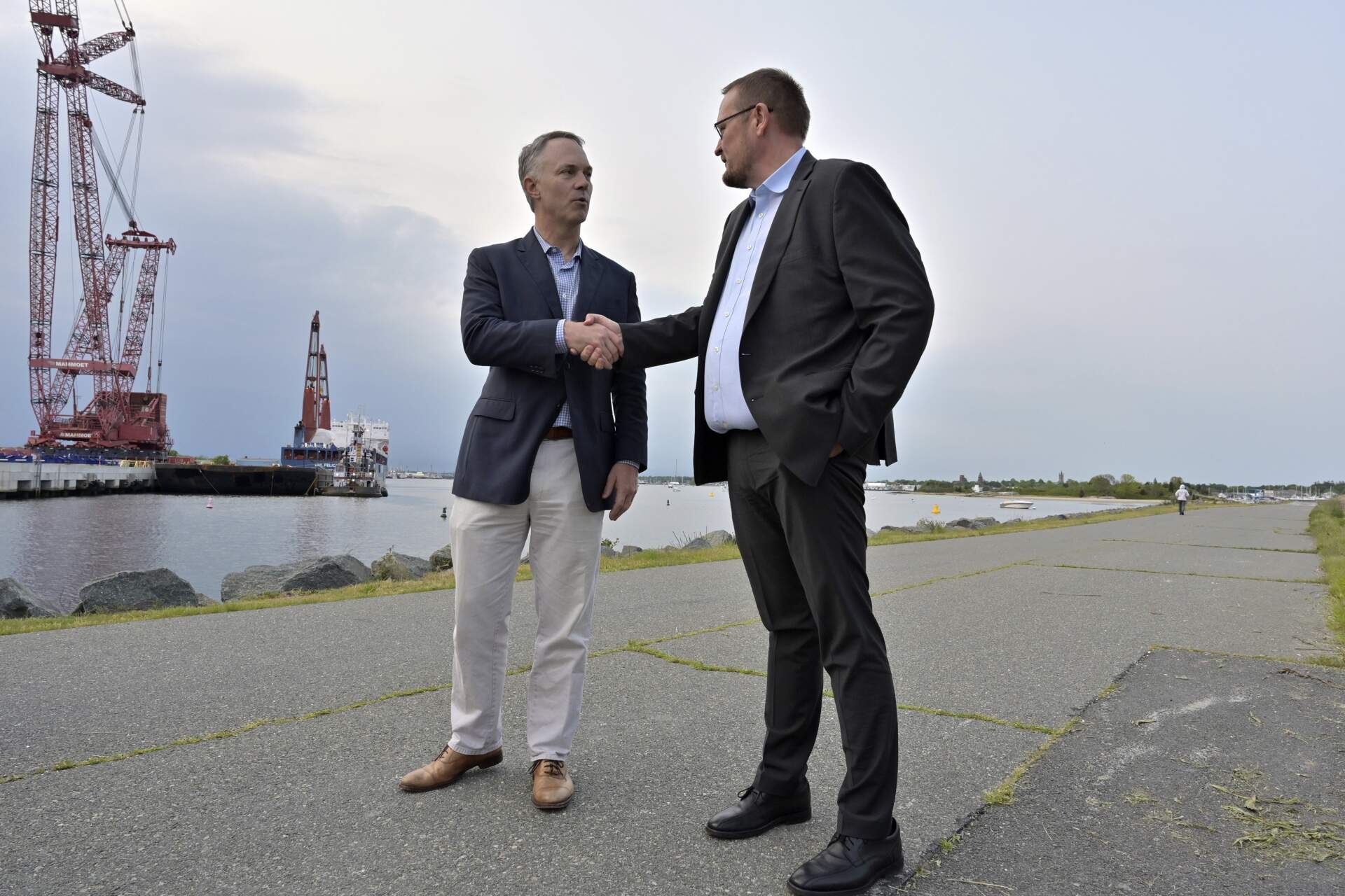 New Bedford Mayor Jon Mitchell and Vineyard Wind CEO Klaus Skoust Moeller shake hands in front of the ship UHL Felicity. (Josh Reynolds/AP)