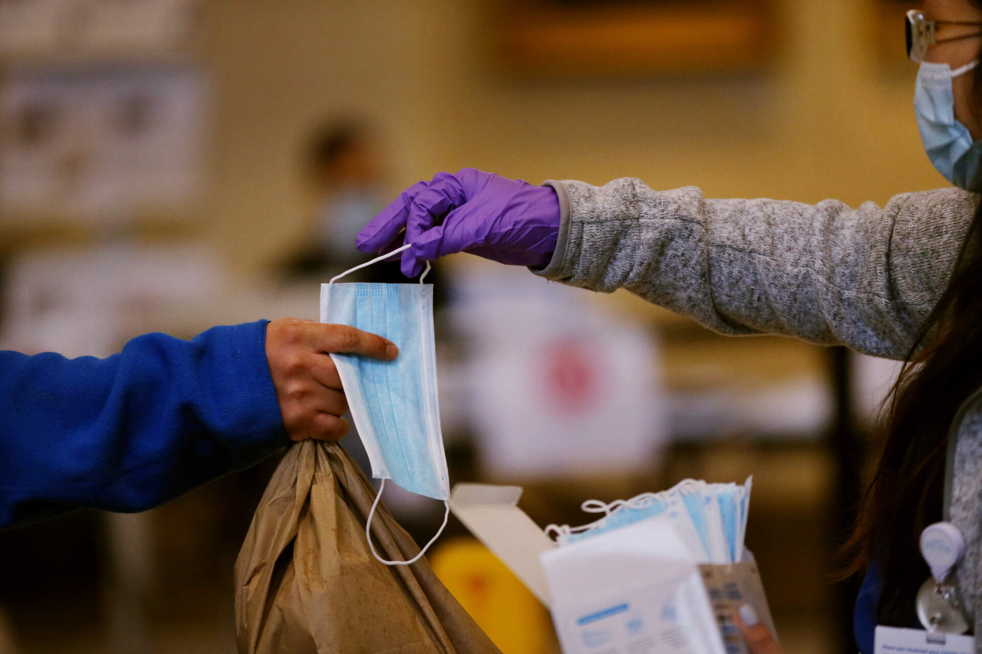 A worker, right, hands masks to employees arriving at Brigham and Women's Hospital in Boston in April of 2020. (Craig F. Walker/The Boston Globe via Getty Images)