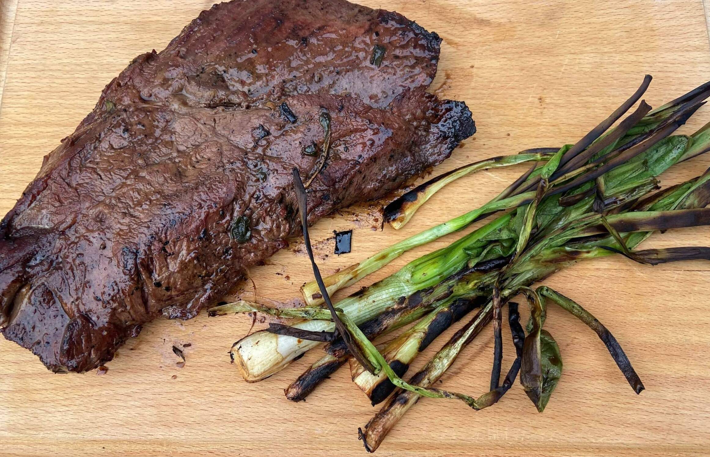 Grilled flat iron steak with soy-ginger marinade and grilled scallions. (Kathy Gunst/Here &amp; Now)