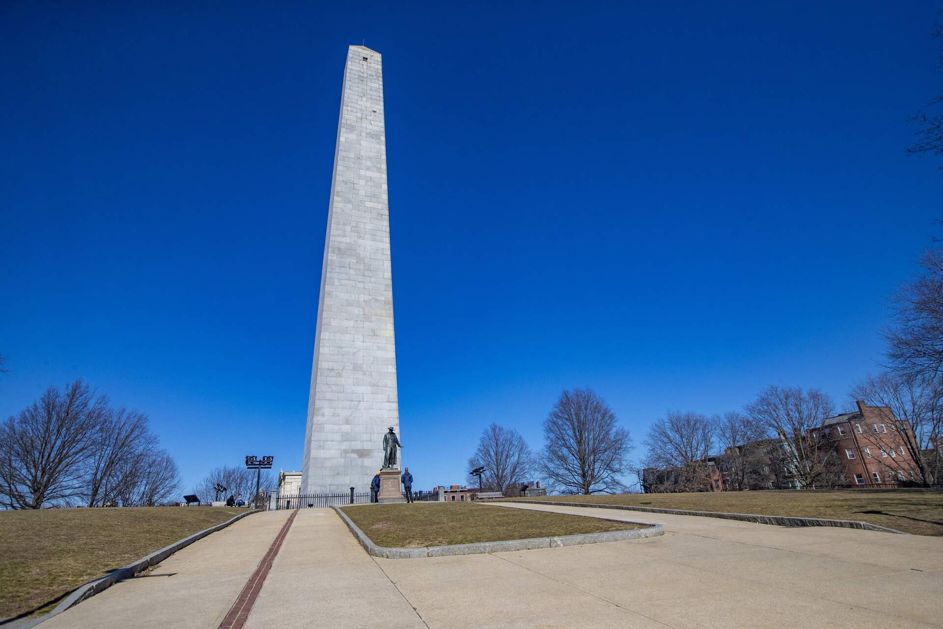 A couple of people stop to read the inscription on a statue on the mall at the Bunker Hill Monument. (Jesse Costa/WBUR)