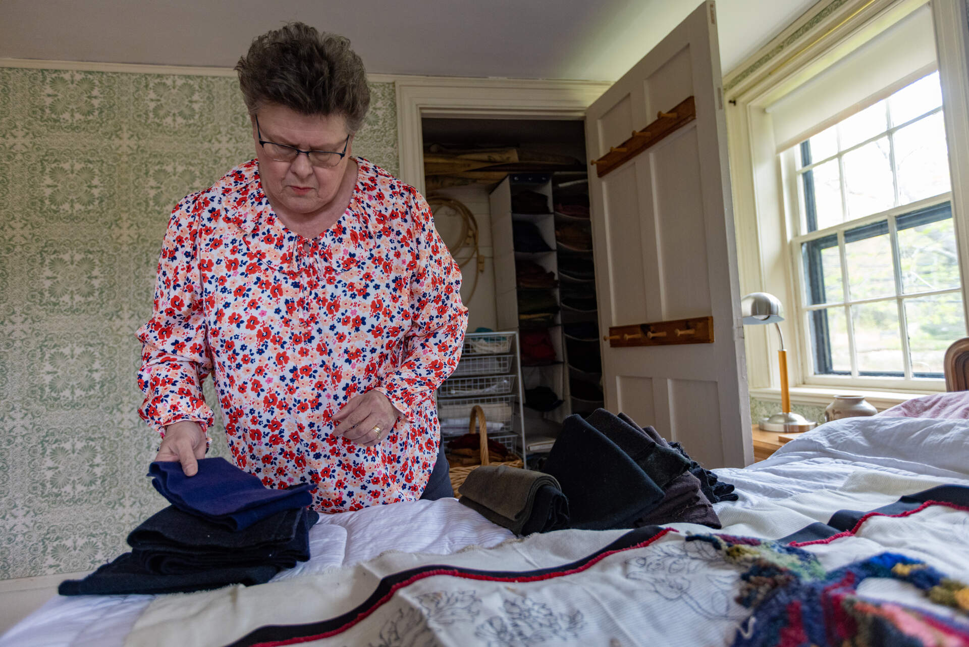 To finish the rug, Jan Rohwetter attempts matching colors of the wool used in the rug from fabric Donna Savastio has stored. (Jesse Costa/WBUR)