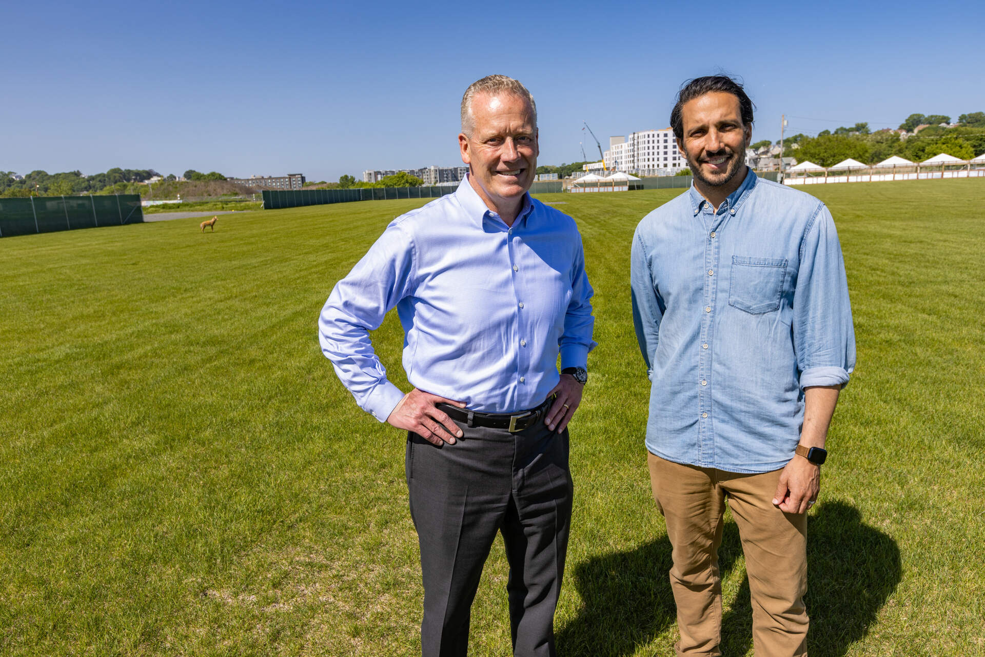 Tom O’Brien, managing partner and CEO of HYM, and Josh Bhatti, vice president of the Bowery Presents Boston, stand on the lawn at Suffolk Downs. (Jesse Costa/WBUR)