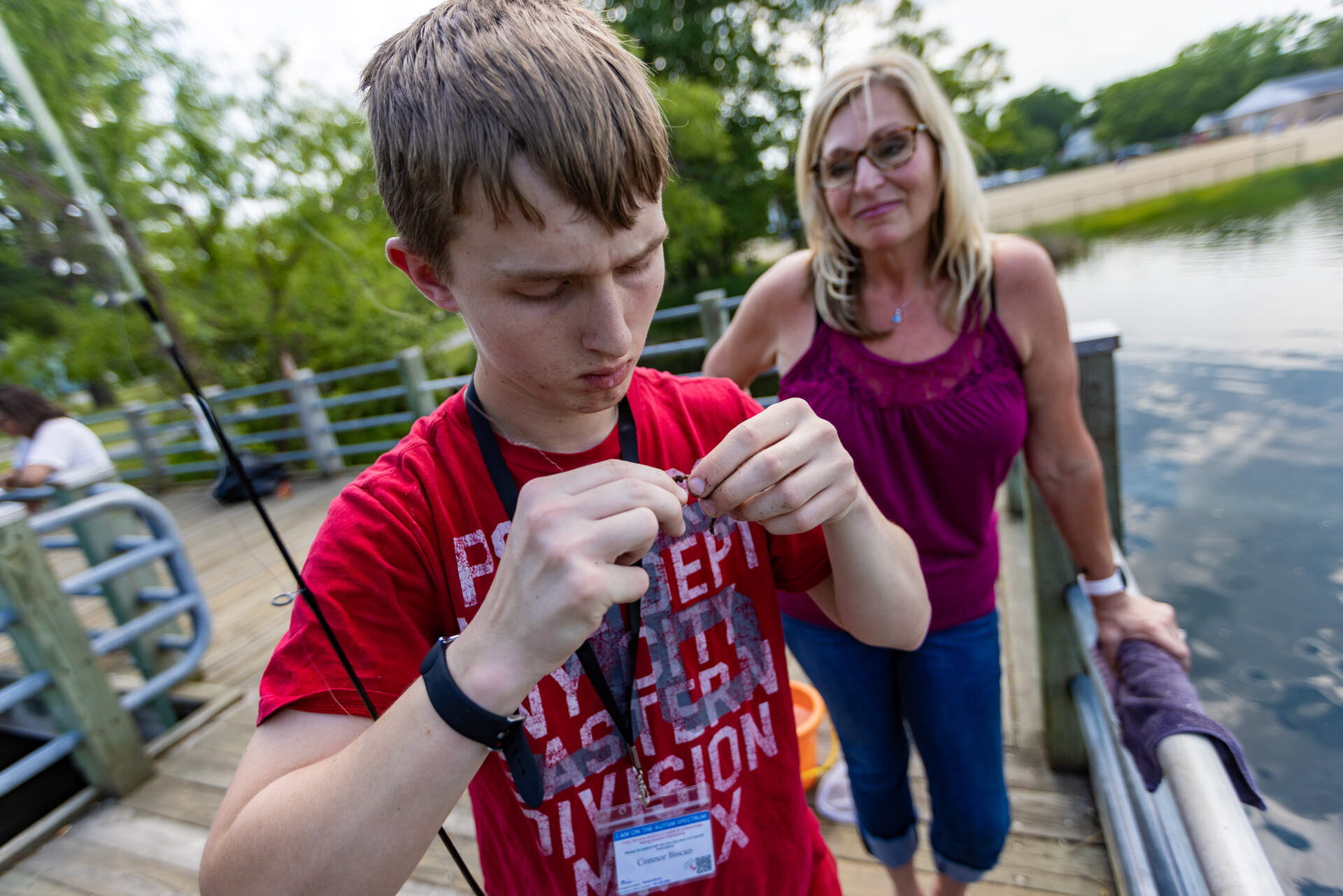 Roberta Biscan watches as her son Connor works to bait a fishing hook on the pier at Silver Lake. (Jesse Costa/WBUR)