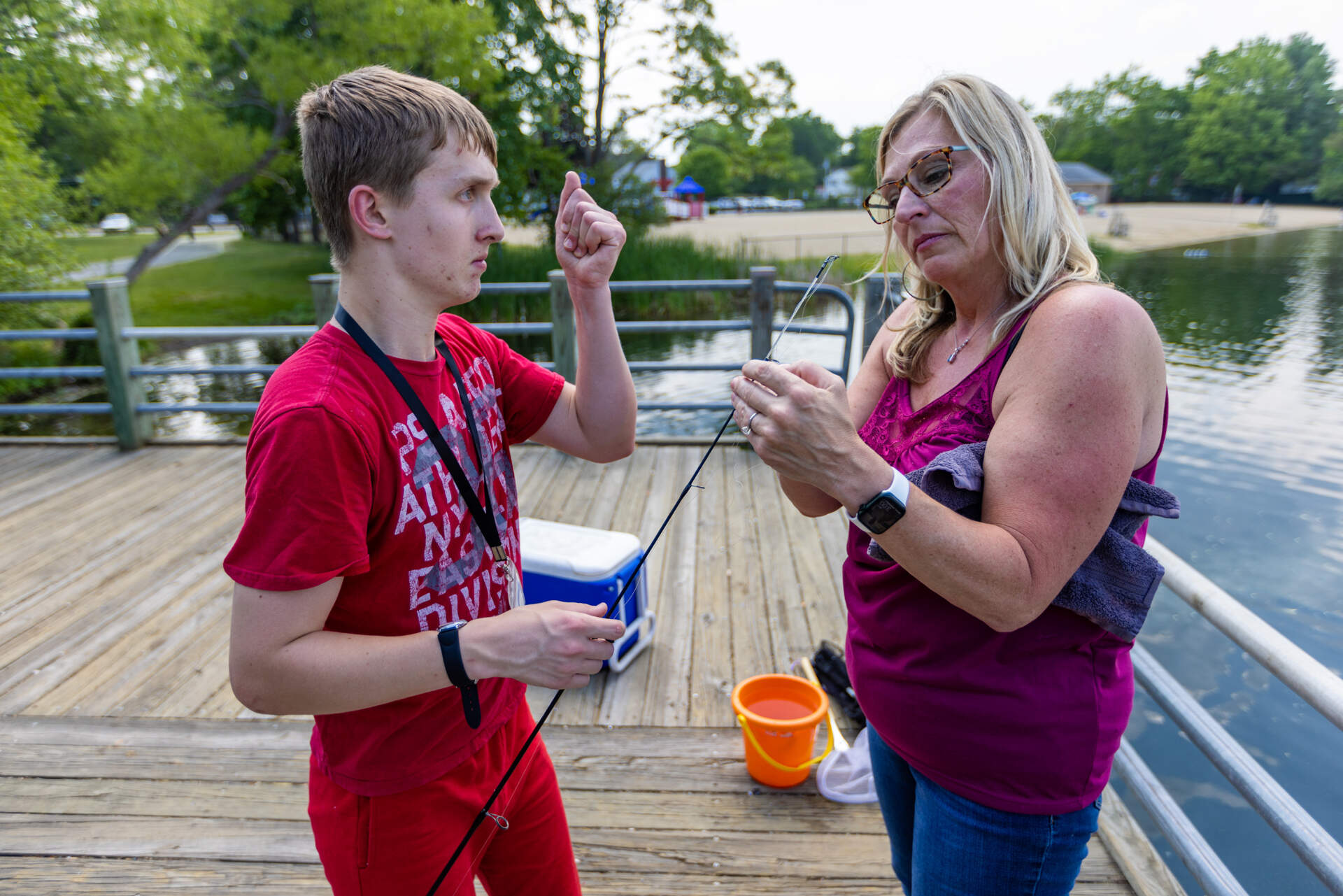 Growing anxious and impatient, Connor Biscan raises his fist toward his mother, Roberta, waiting for her to untangle the fishing line for him. (Jesse Costa/WBUR)